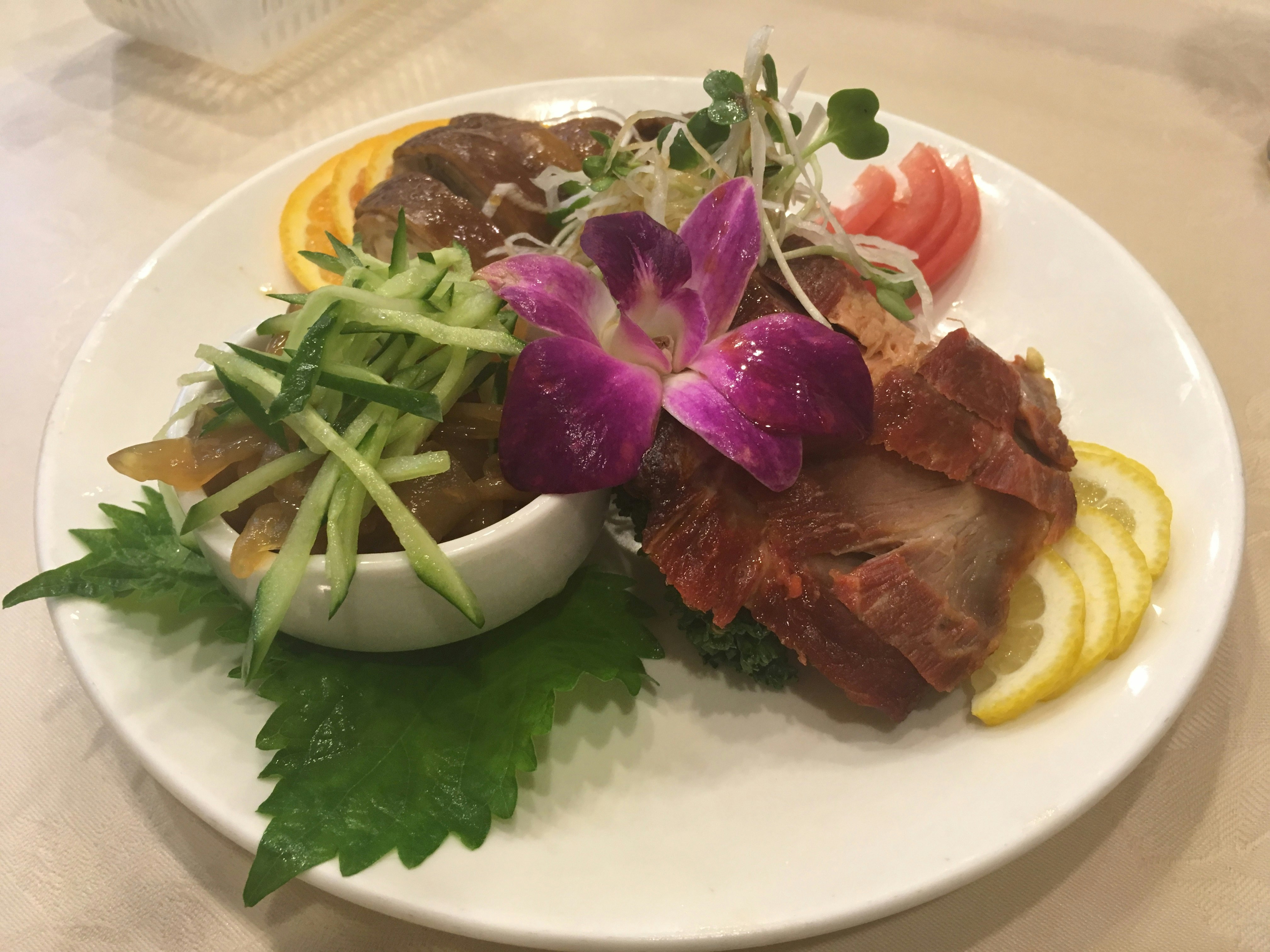 meat dish plate garnished with orchid and lemon