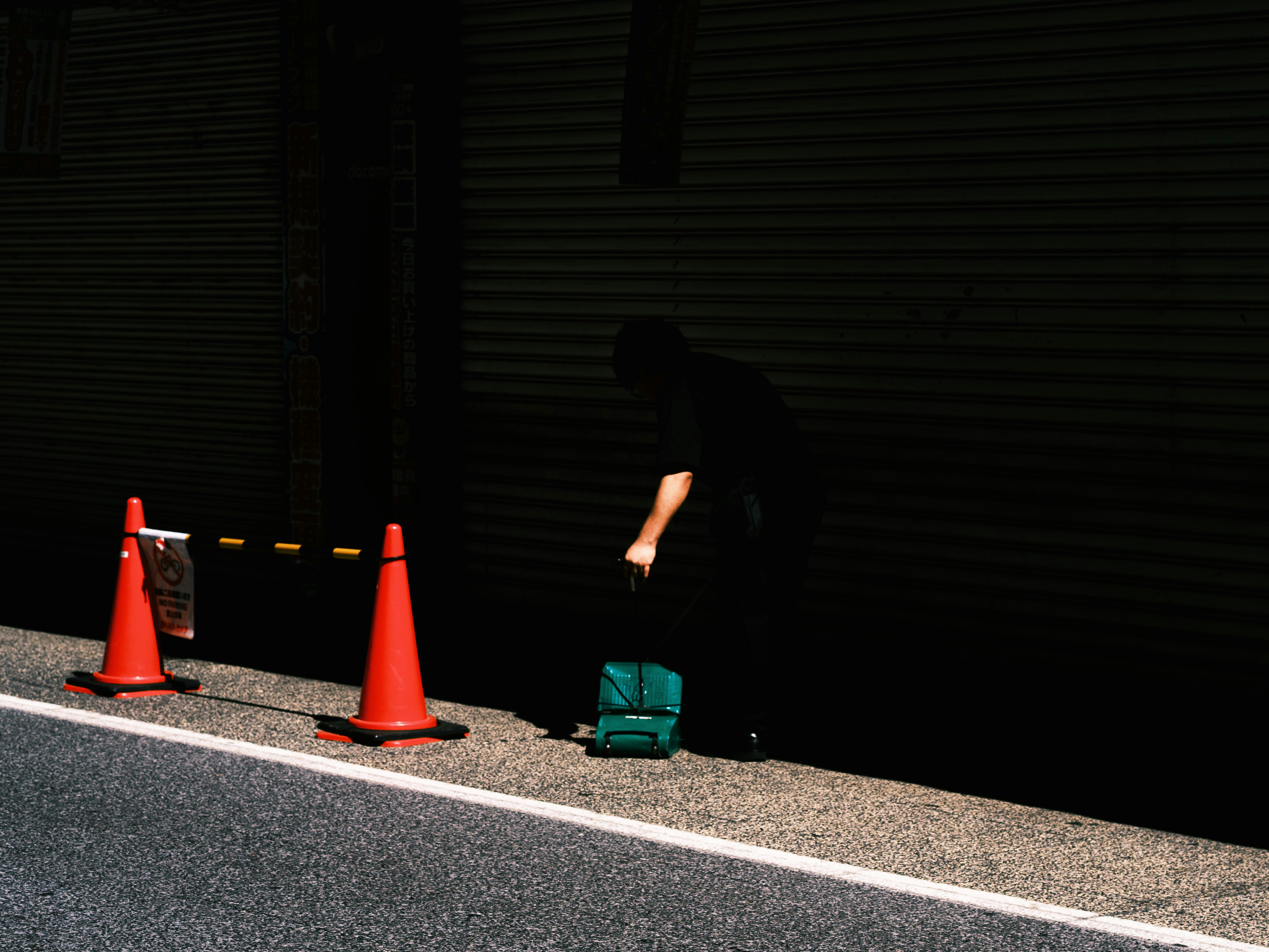 night street scene with traffic cones and a green toolbox by the roadside