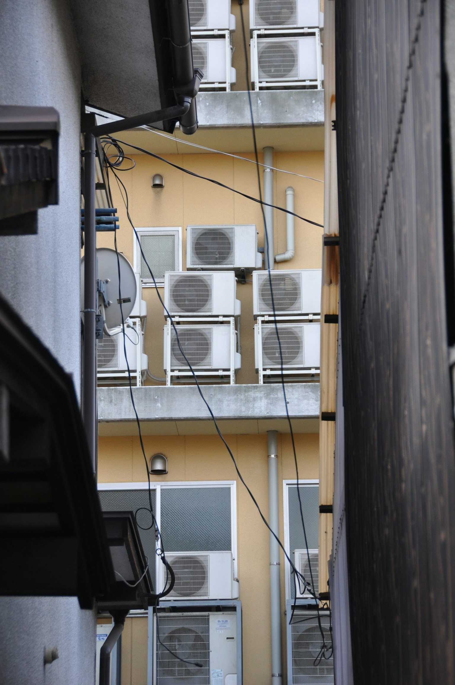 狭窄小巷中建筑外观，配有空调单元