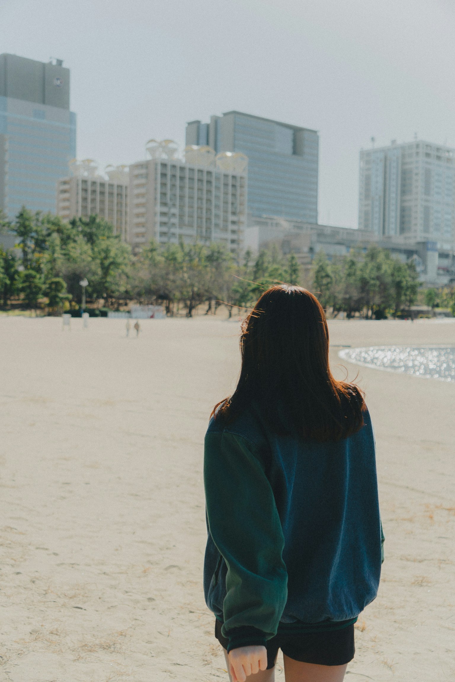 背對沙灘的女性和背景中的摩天大樓
