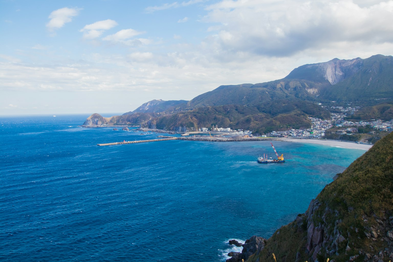 Vista panoramica di una città costiera con montagne e oceano blu