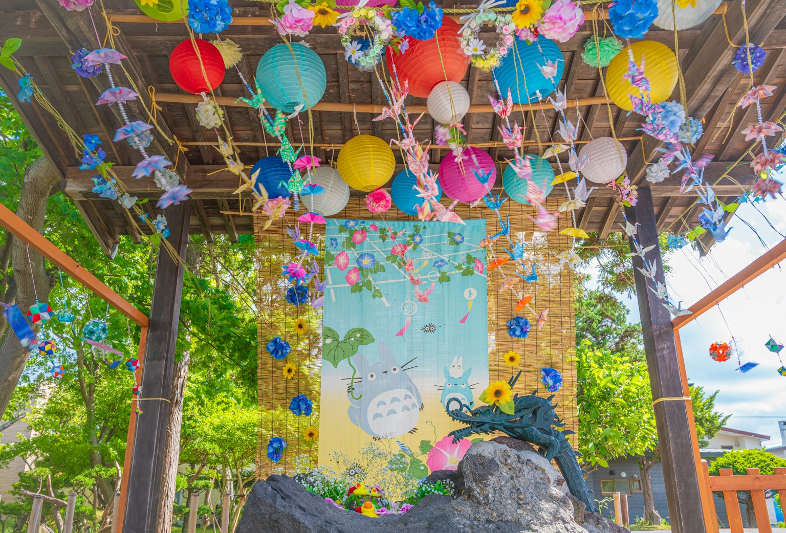 Faroles coloridos y decoraciones florales adornan una escena de pabellón al aire libre