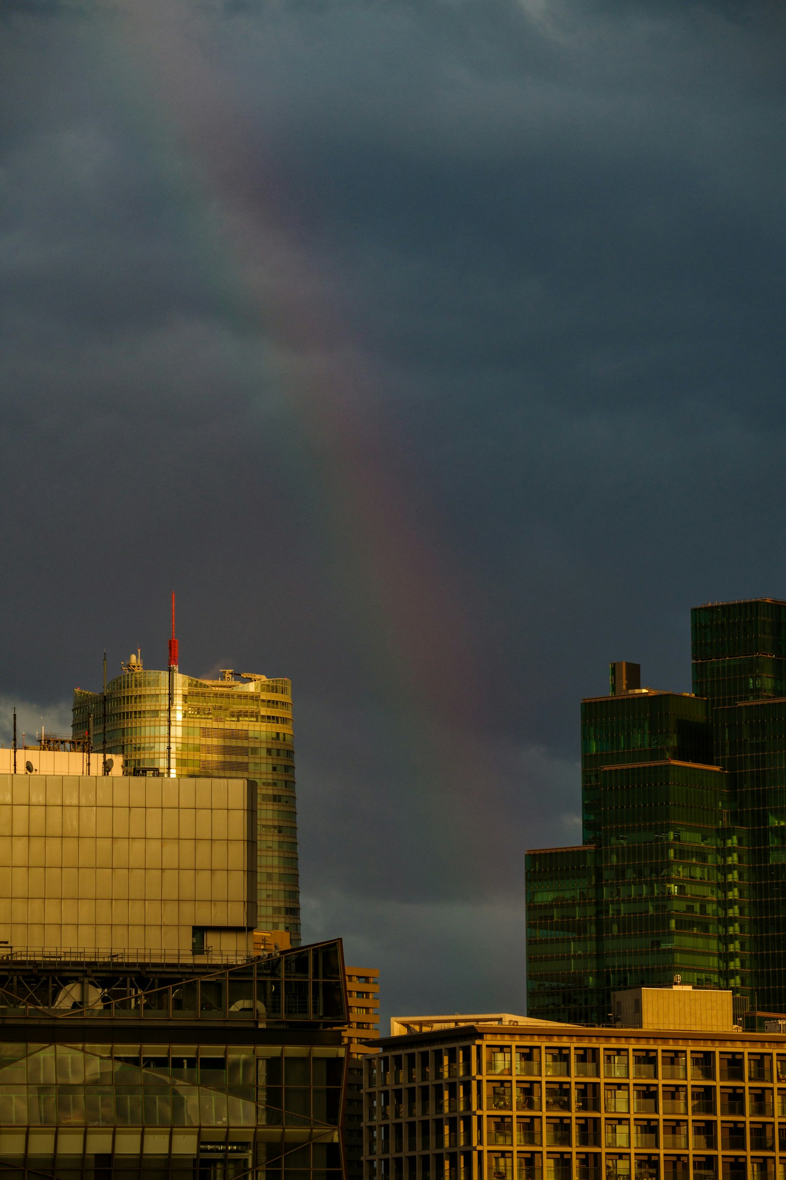 Regenbogen, der durch dunkle Wolken über der Skyline der Stadt erscheint