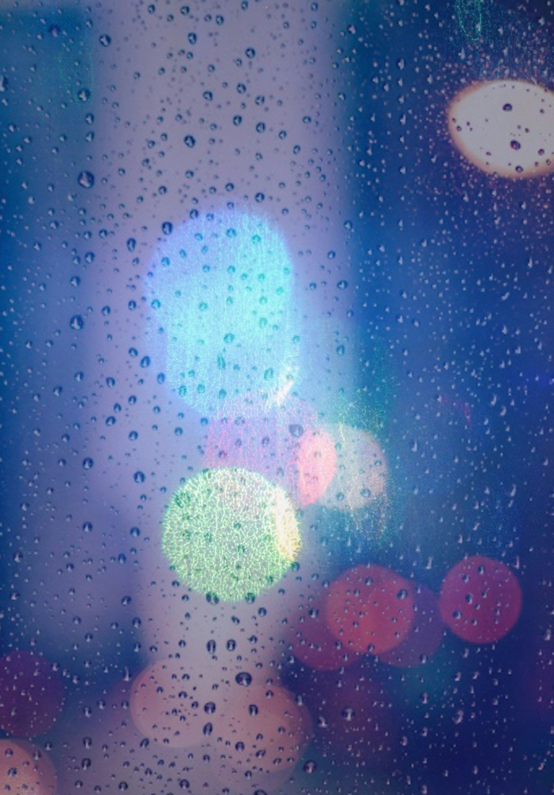 雨粒のついた窓ガラス越しの街の灯り