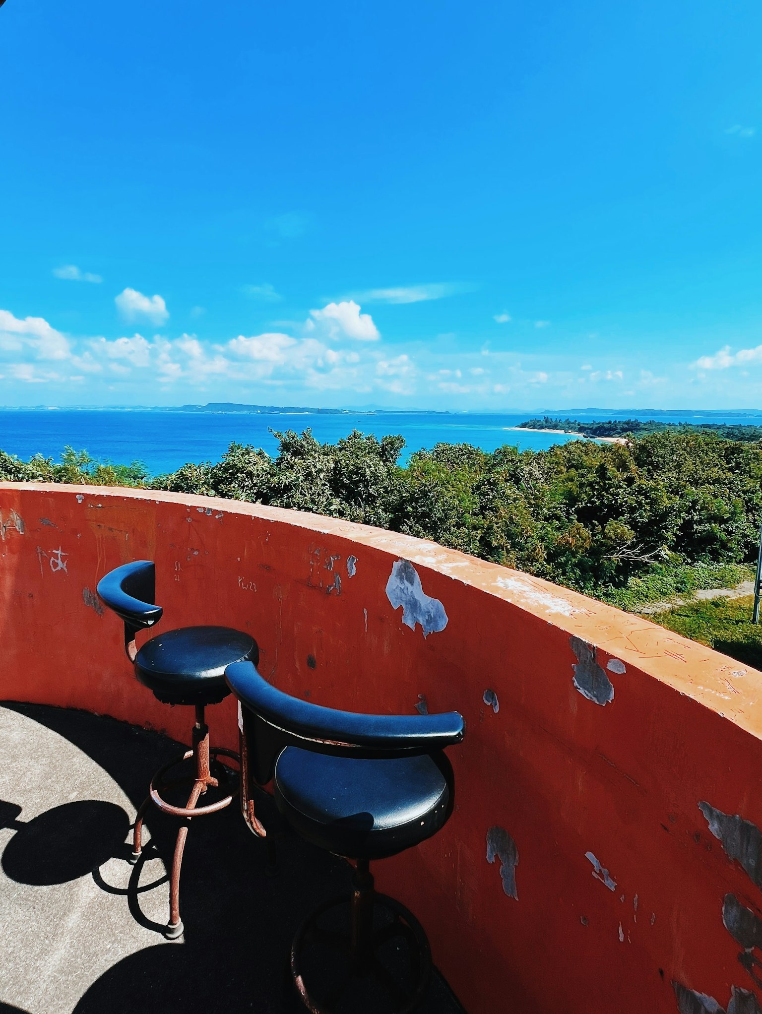 Sedie nere su un balcone che si affaccia sull'oceano e sul cielo blu