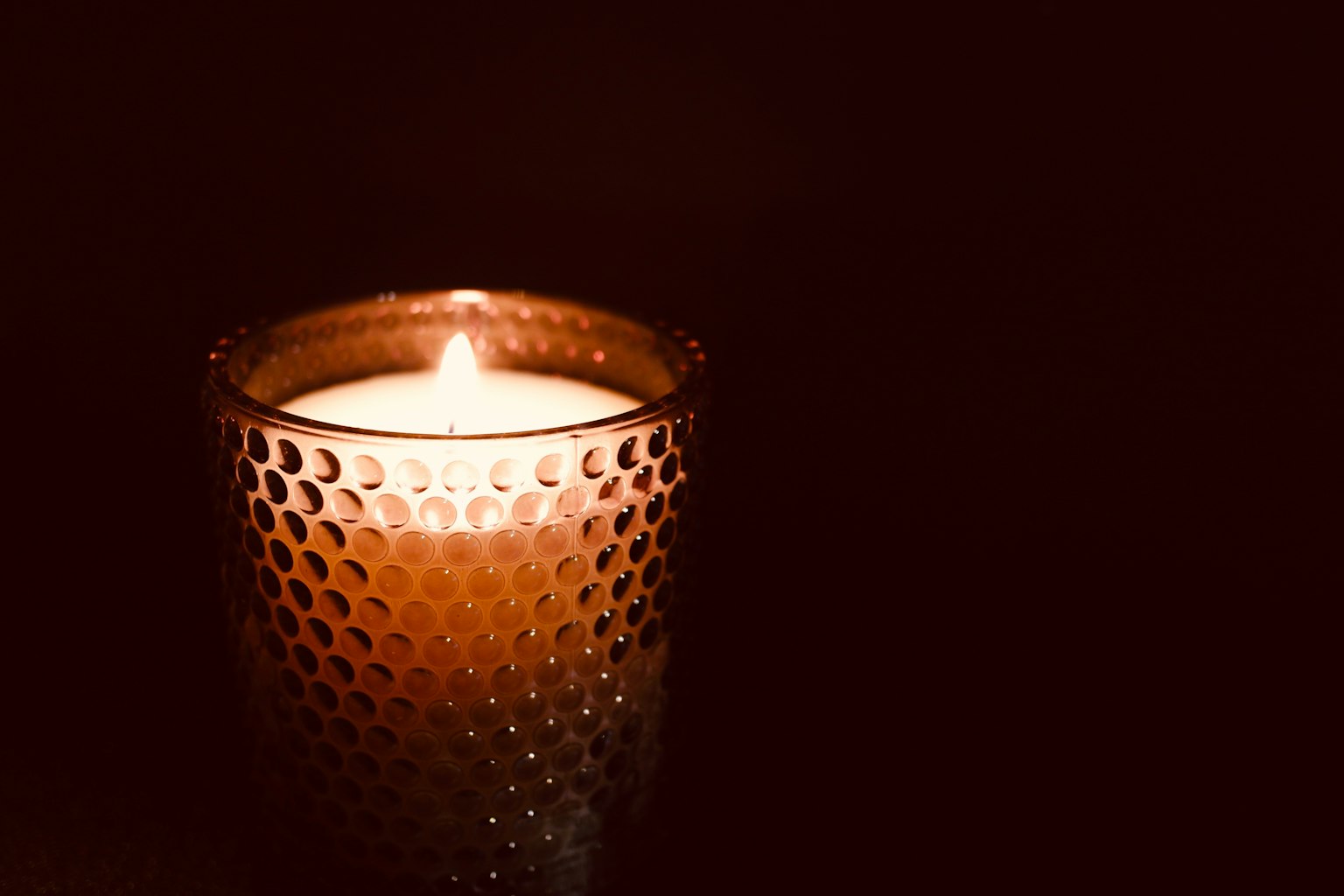 Une bougie émettant une lumière chaleureuse dans un porte-bougie décoratif