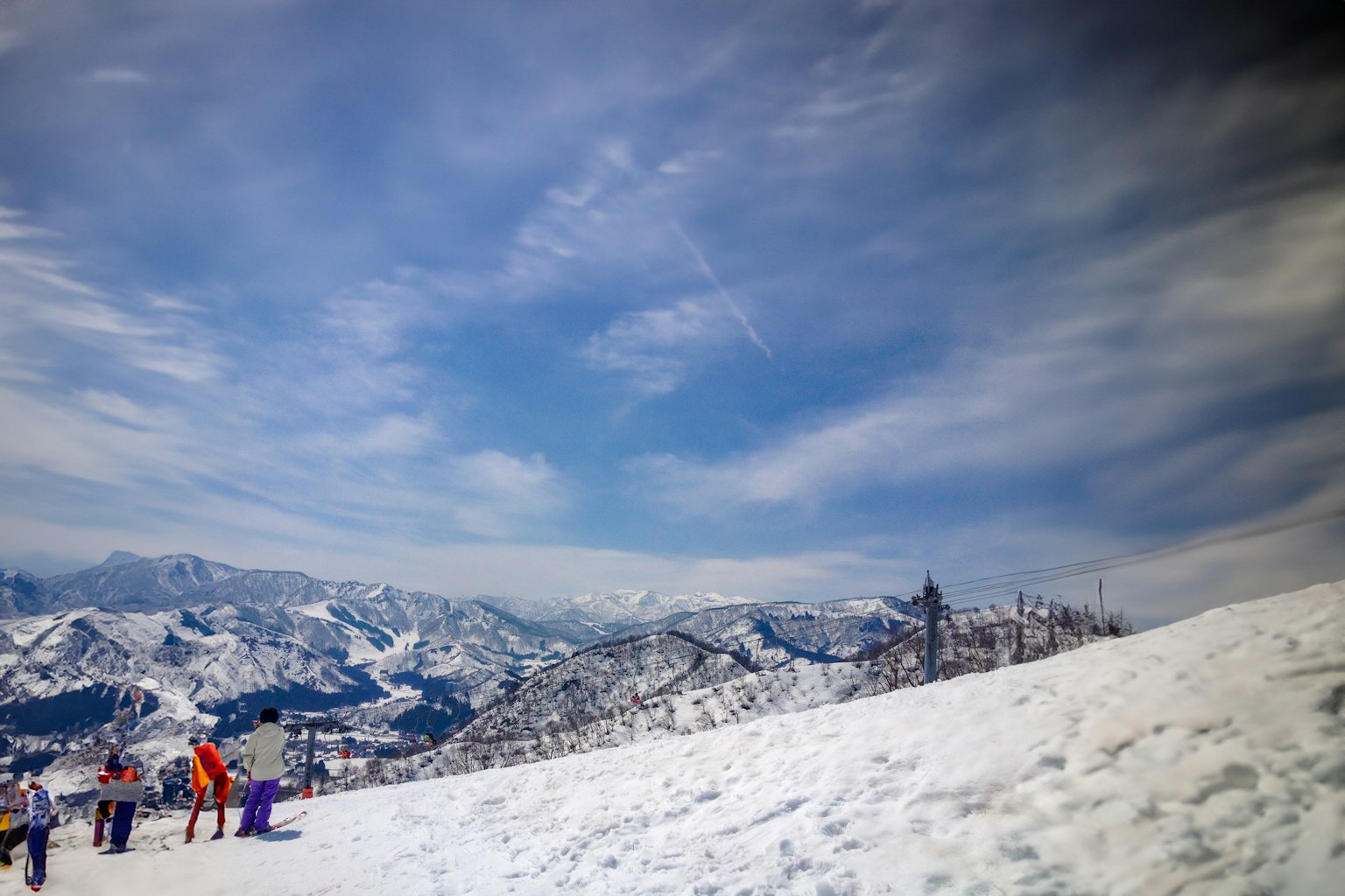 Schnee bedeckte Berge und blauer Himmel mit Skifahrern