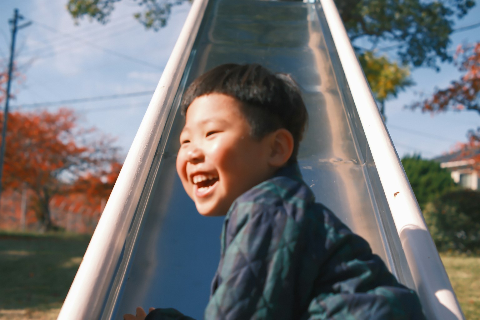 滑り台で遊ぶ笑顔の男の子 秋の風景