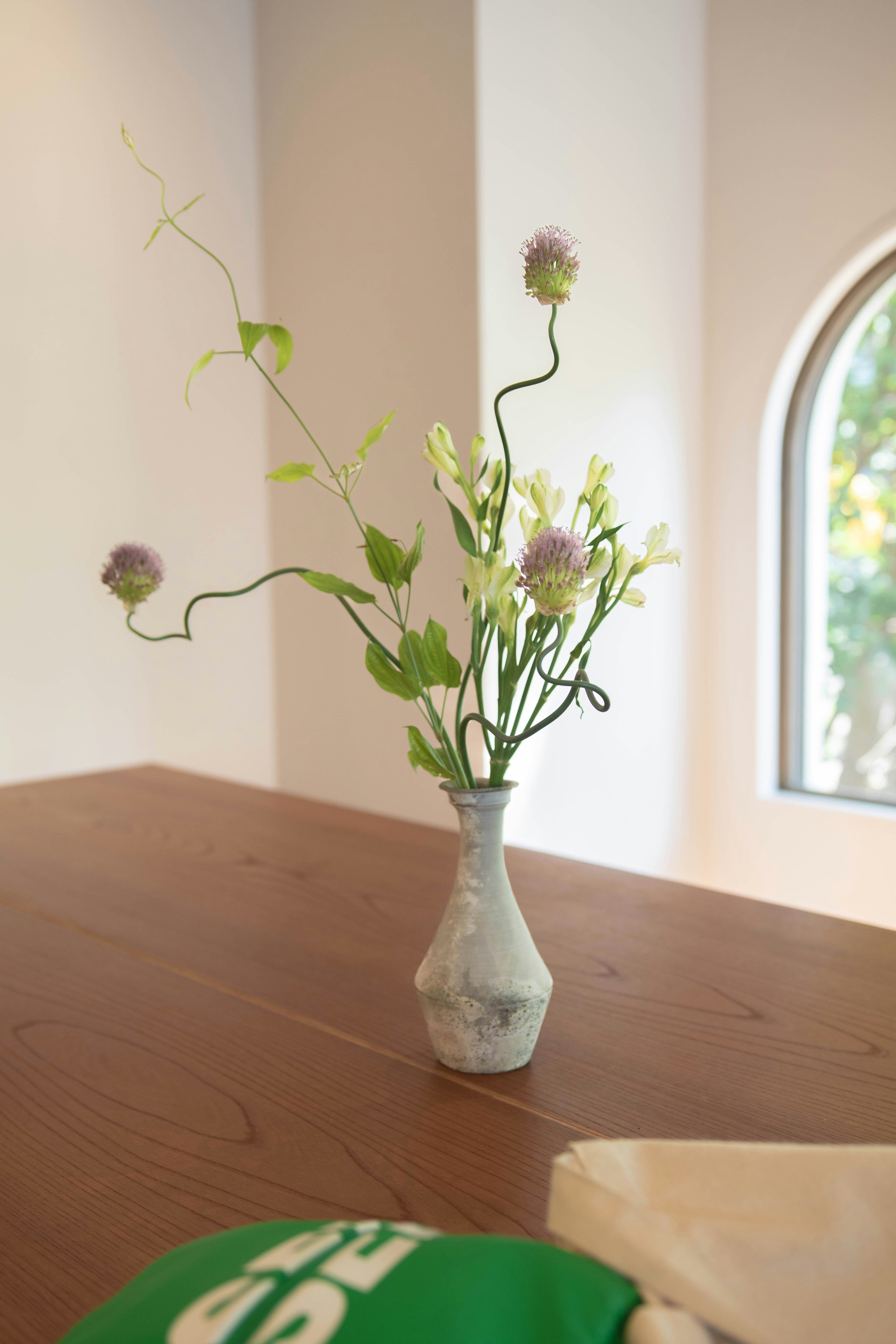 窓辺のテーブルに生けられた花の花瓶