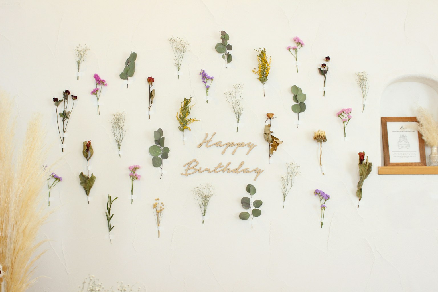 A wall decorated with dried flowers and the text 'Happy Birthday'