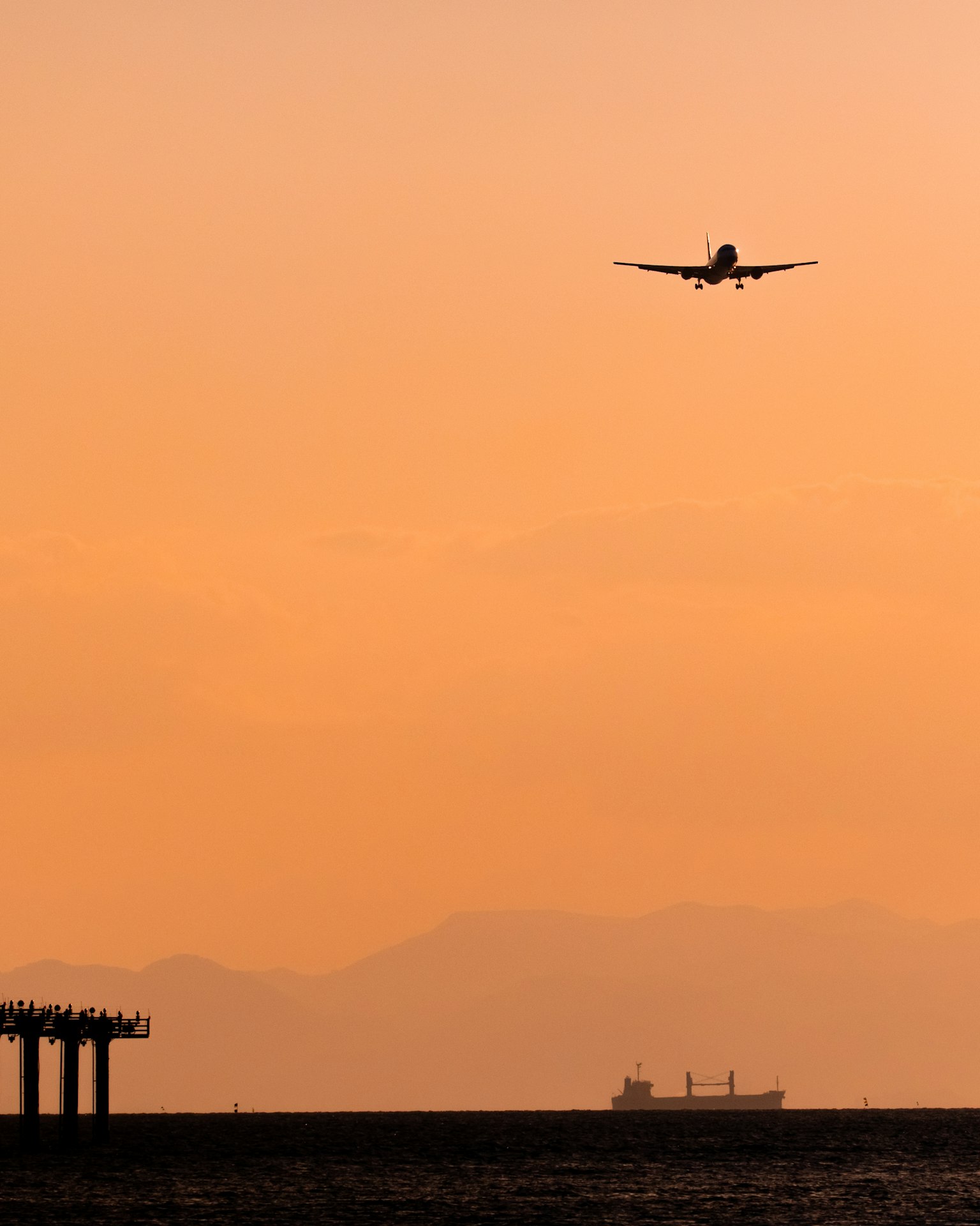 Silhouette di un aereo che vola nel cielo al tramonto sopra l'oceano