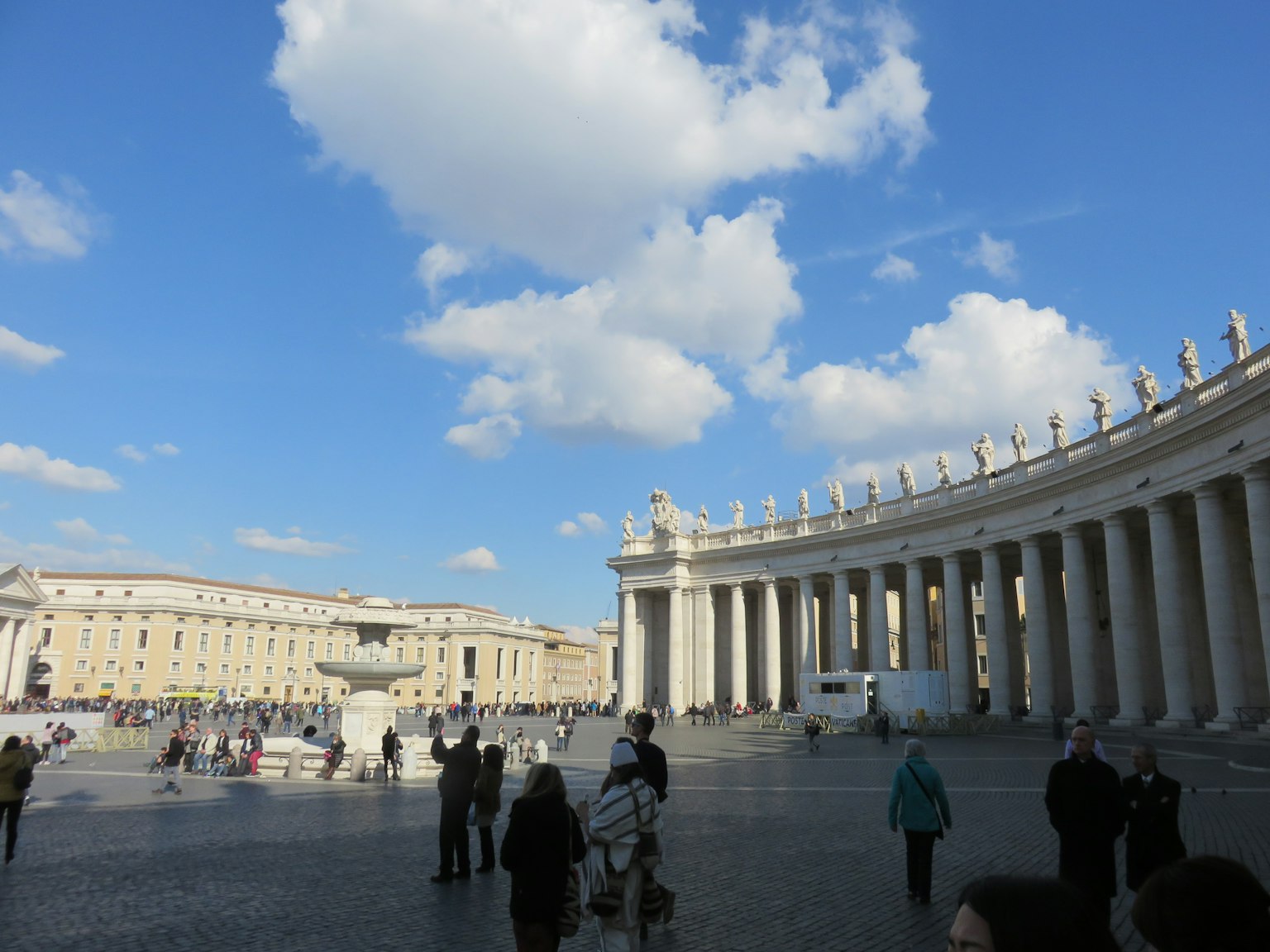 Vista de la Plaza de San Pedro en el Vaticano cielo azul y nubes blancas columnas de mármol y visitantes