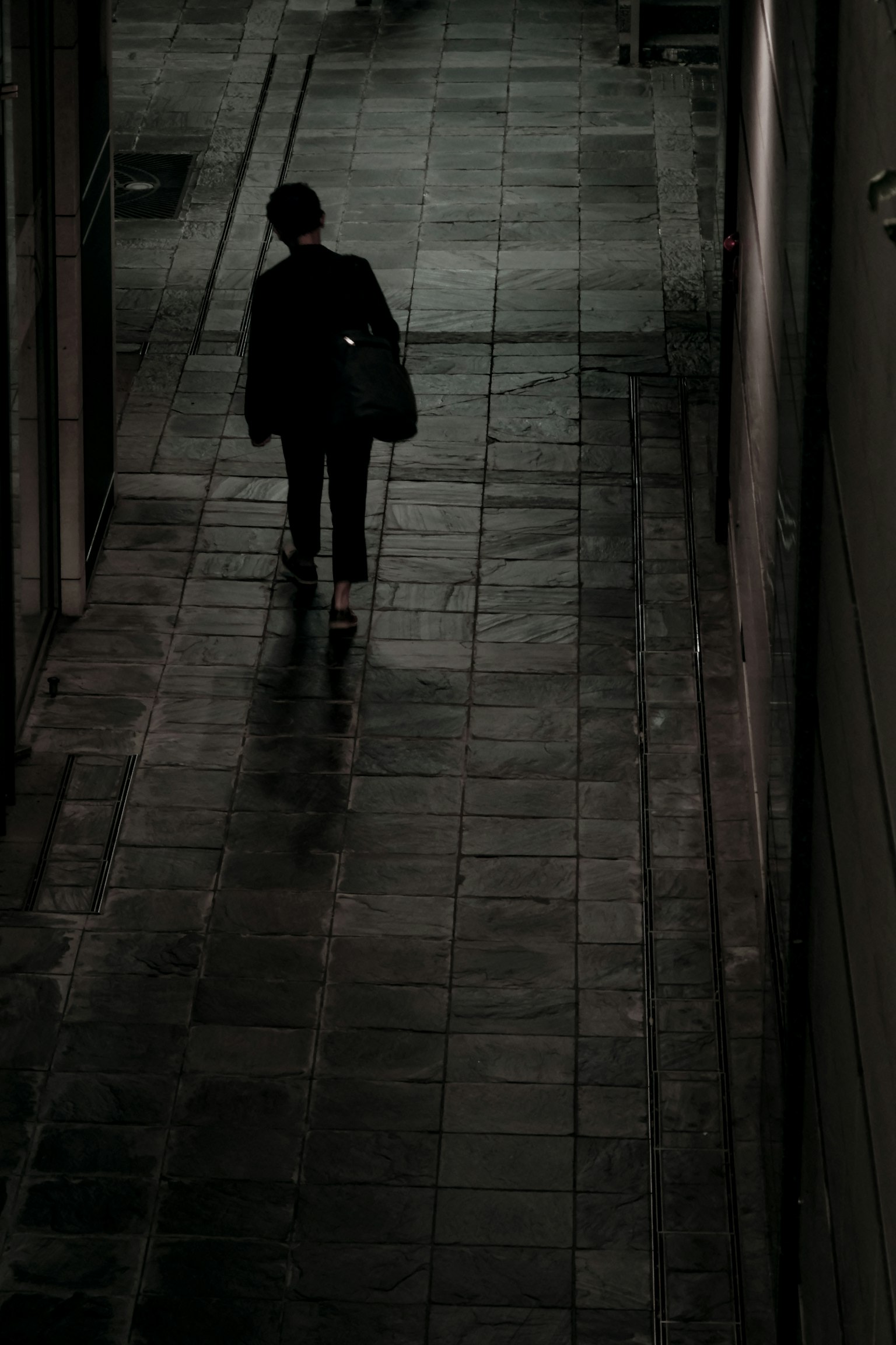 Silhouette di una persona che cammina in un vicolo debolmente illuminato