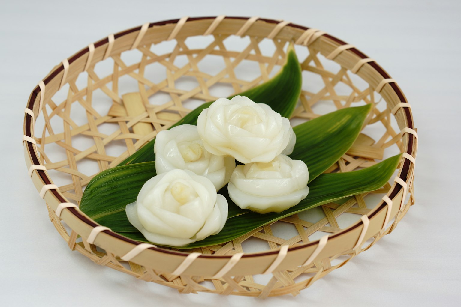 一個竹籃裡放著白色花朵和綠色葉子