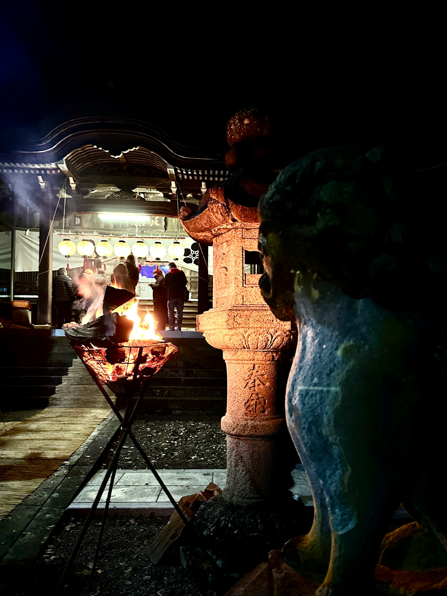 Scene of fire and sculptures at a temple at night