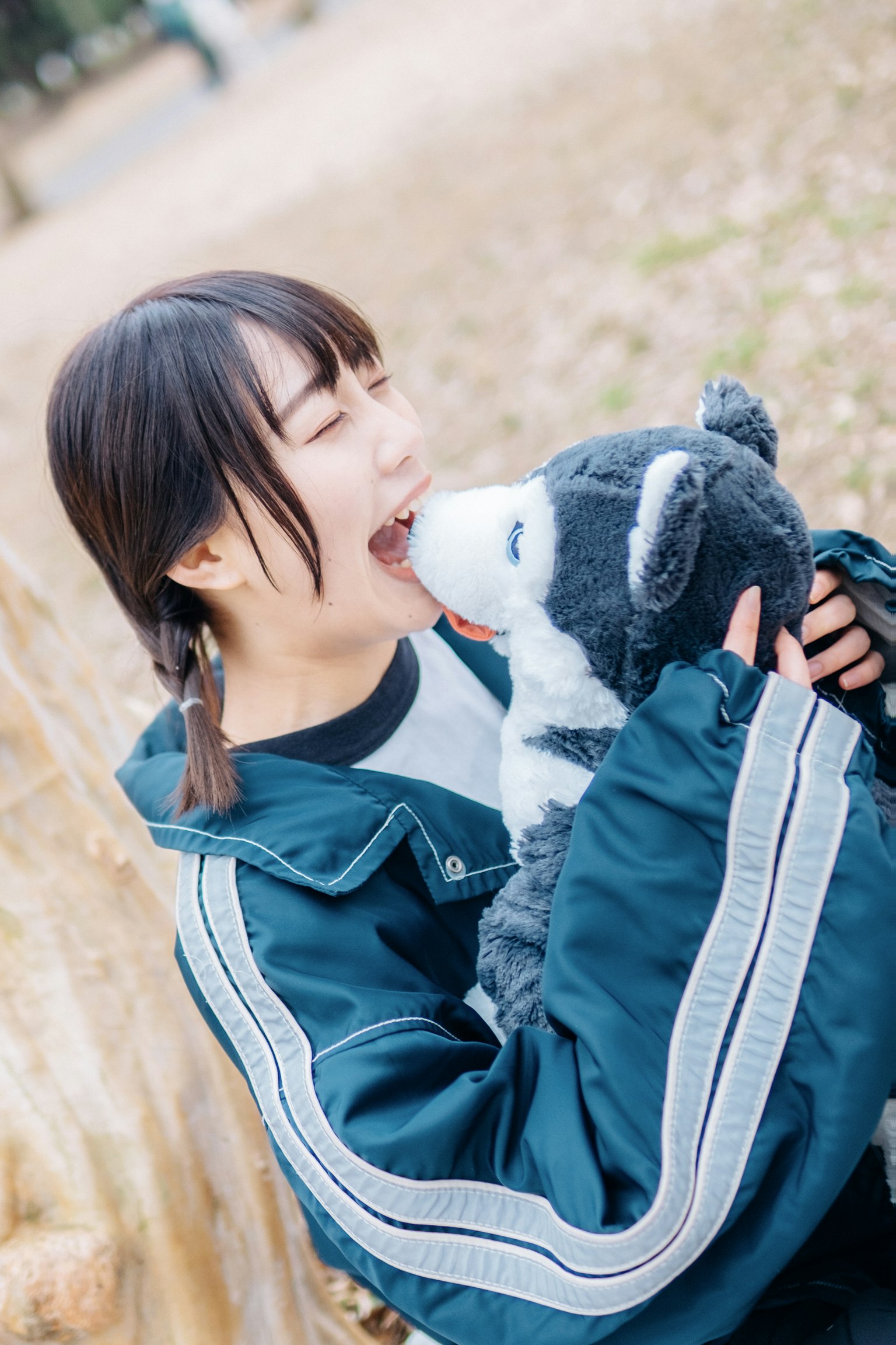 Frau in blauer Jacke spielt mit einem Wolf Plüschtier