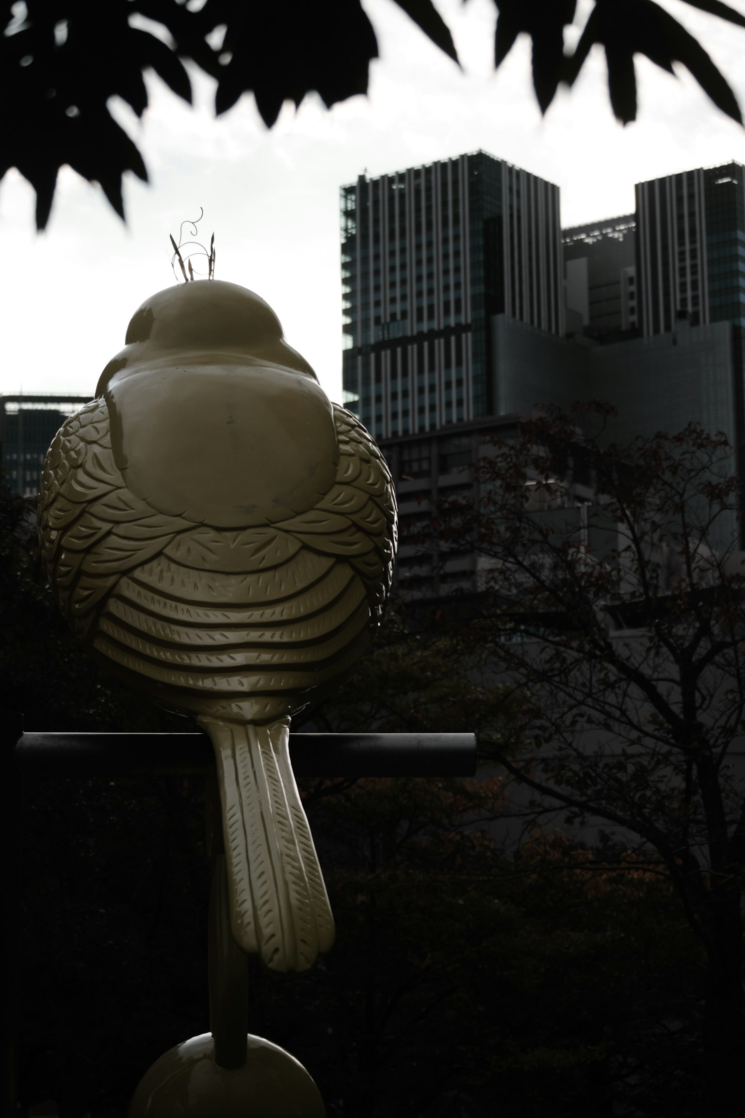 Goldene Vogelskulptur mit Wolkenkratzern im Hintergrund