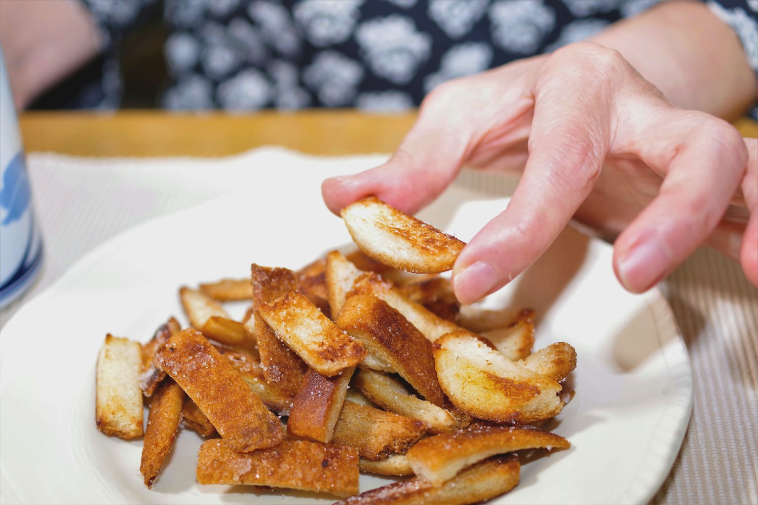 Una mano alcanzando una pila de rodajas de papa fritas crujientes