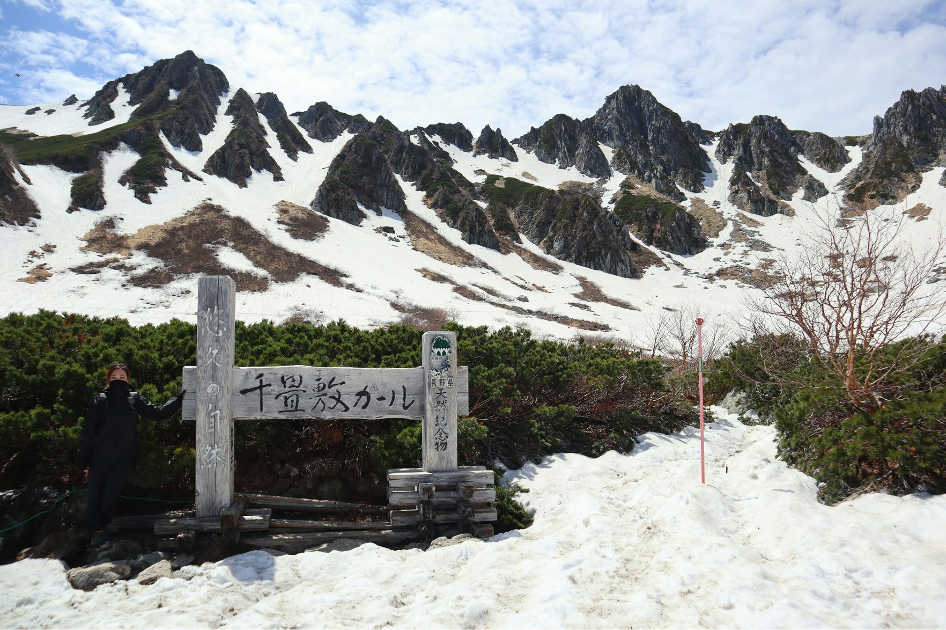雪の千畳敷カールで見上げる宝剣岳の岩と雲の絶景