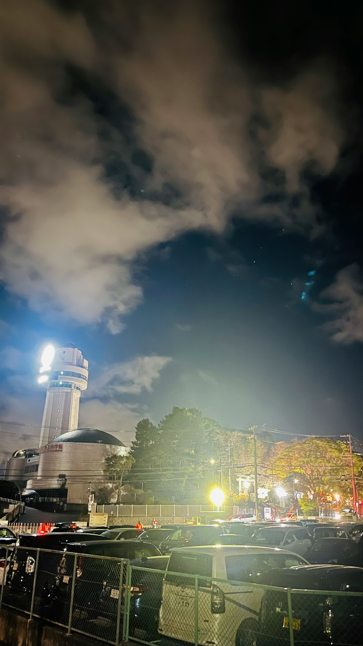 Cielo notturno con nuvole e una torre luminosa