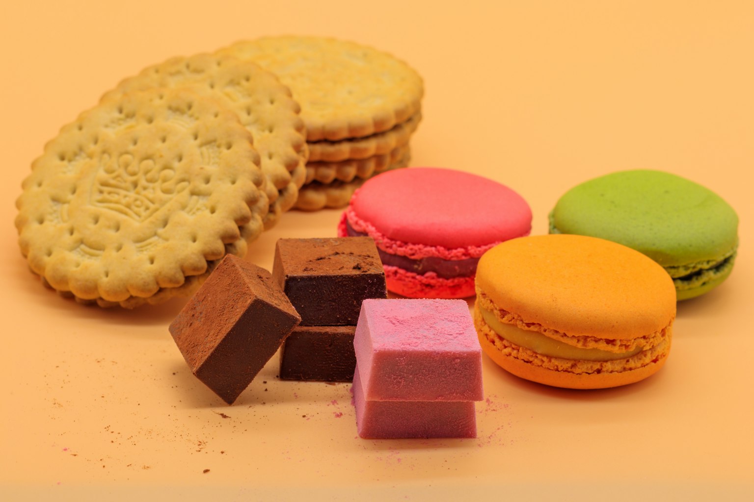 Bunte Macarons und Schokoladenstücke auf einem Teller angeordnet
