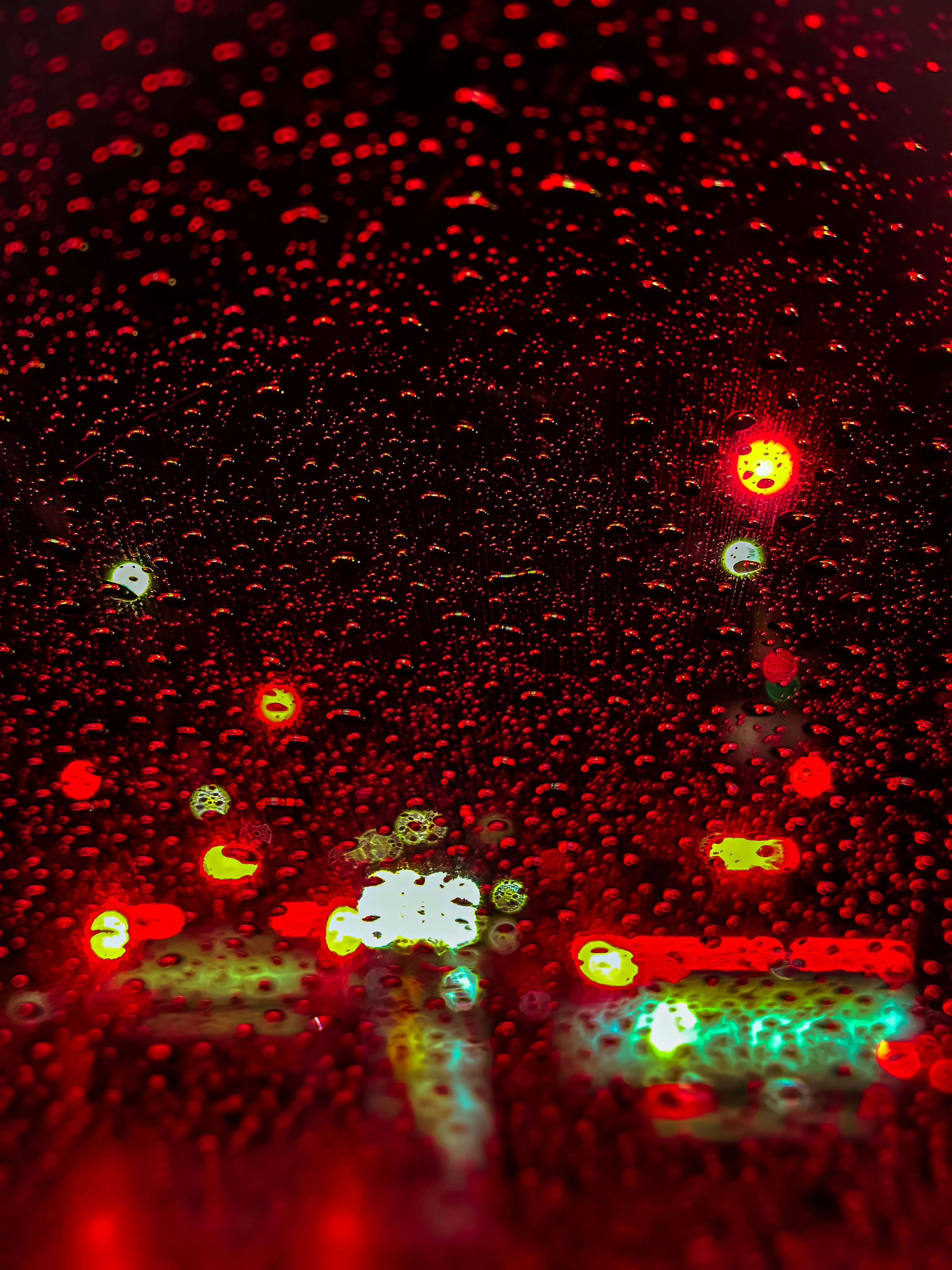 雨の中の車のフロントガラス越しのぼやけた光と色とりどりの光点