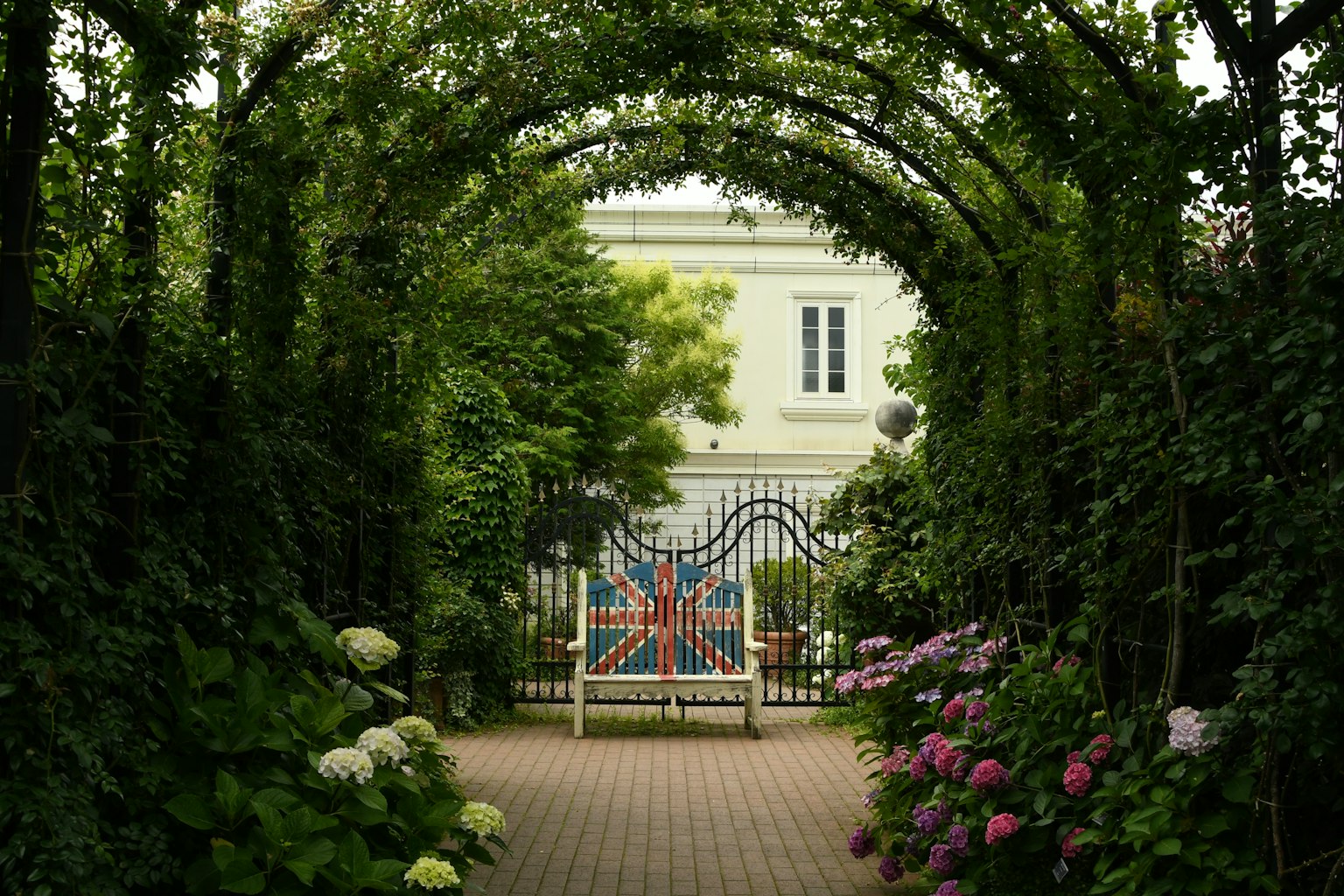 Sentier à travers une arche verte avec un banc Union Jack