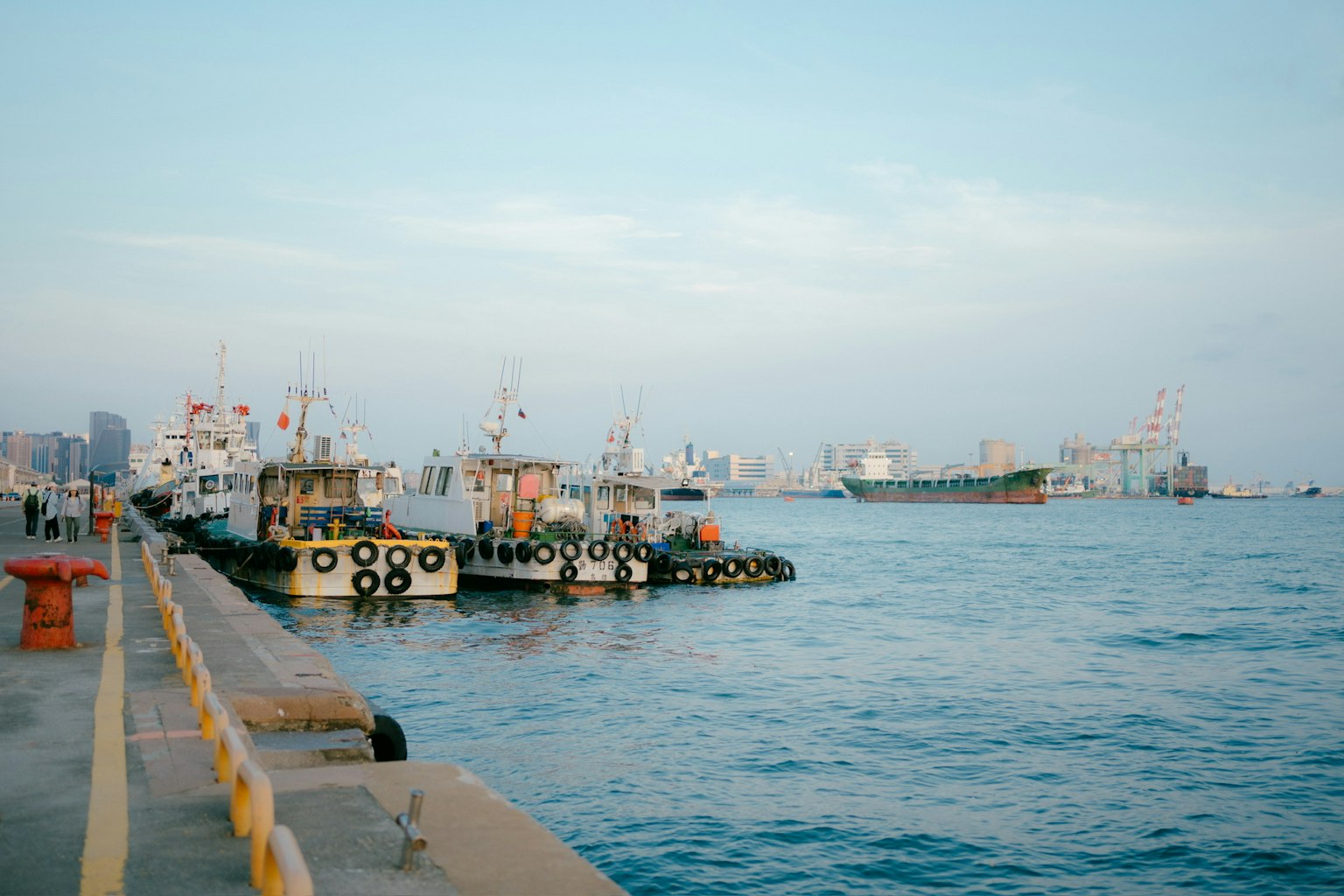 View of fishing boats and cargo ships docked at the harbor