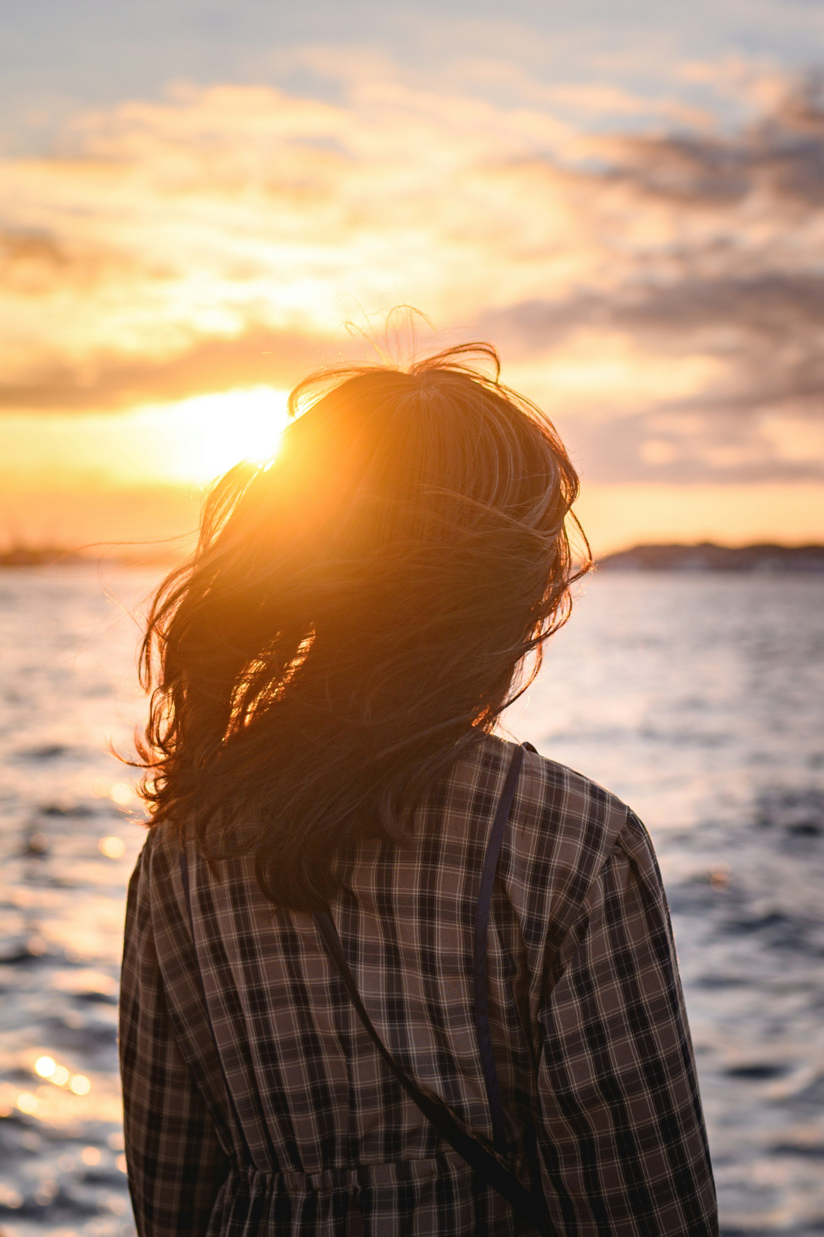 夕日に照らされる海辺の横顔の女性