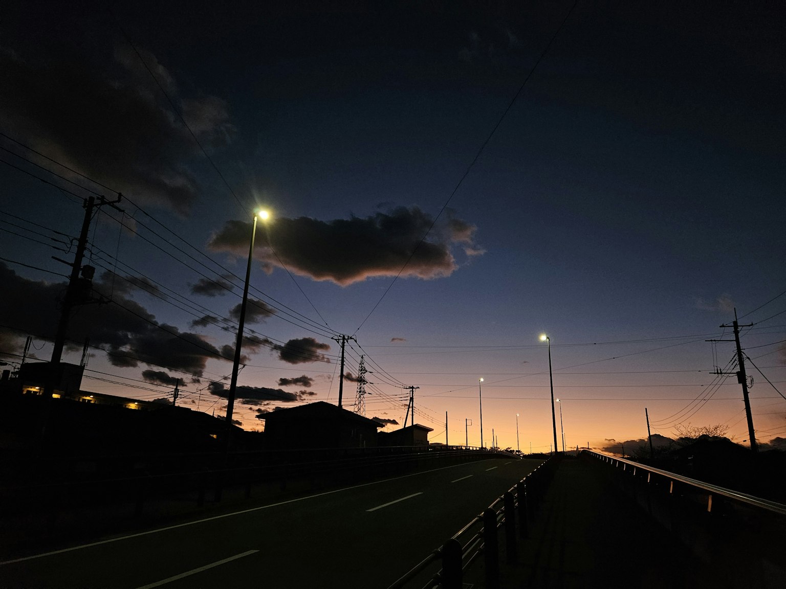 Scène crépusculaire d'une route avec des lampadaires et des nuages
