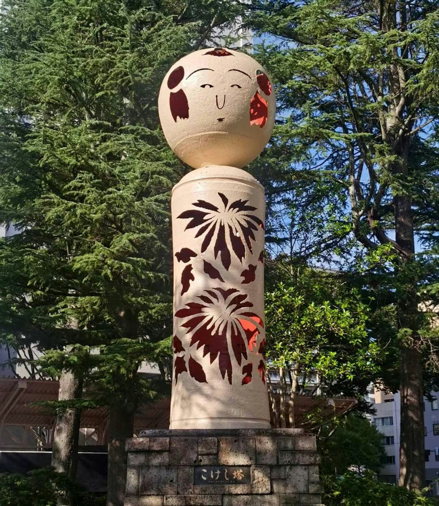Holzskulptur mit roten Blumenmustern und einem lächelnden Gesicht