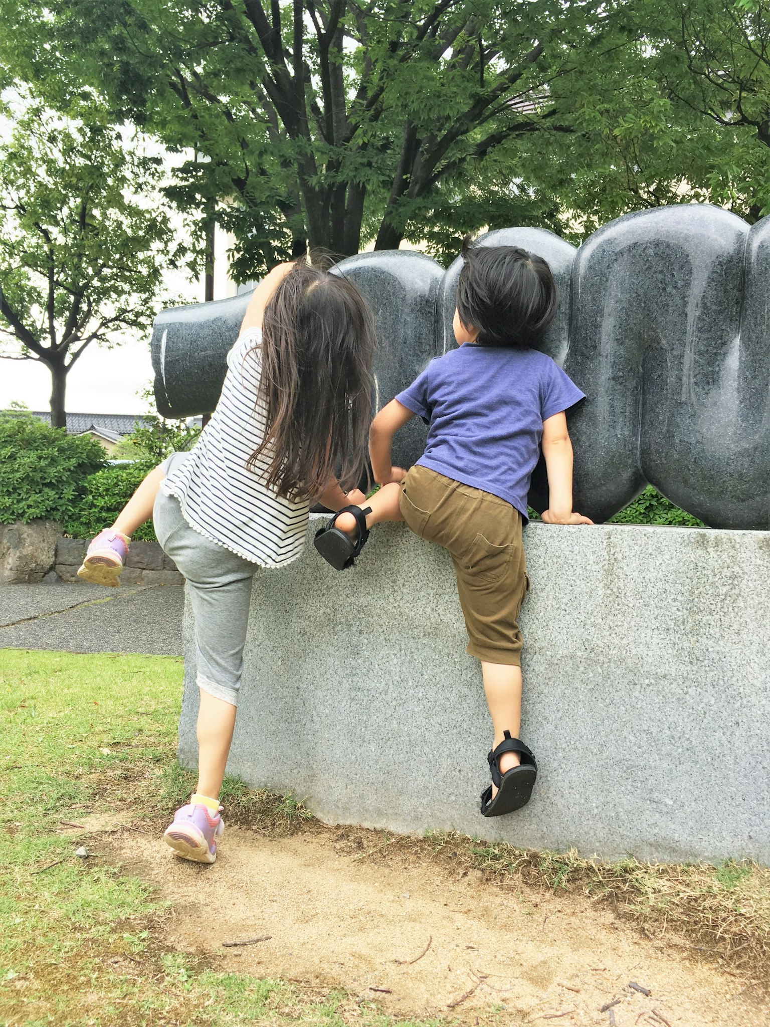 Bambini che scalano una grande scultura in un parco