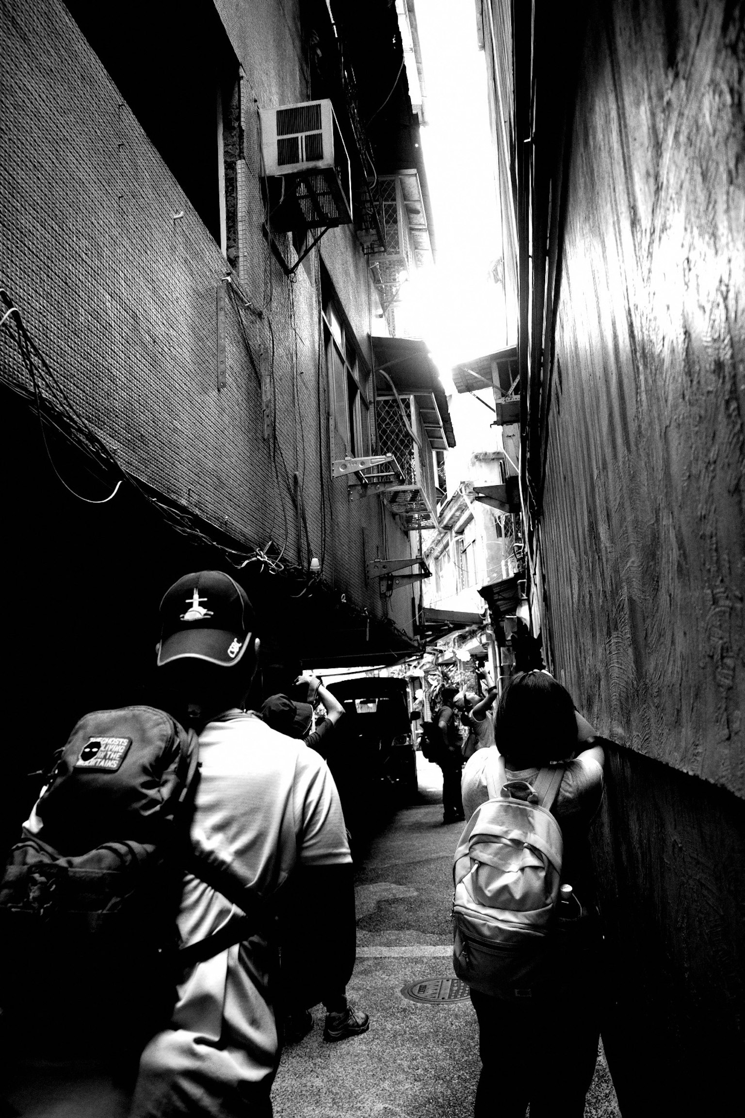 狭い路地を歩く人々のモノクロ写真