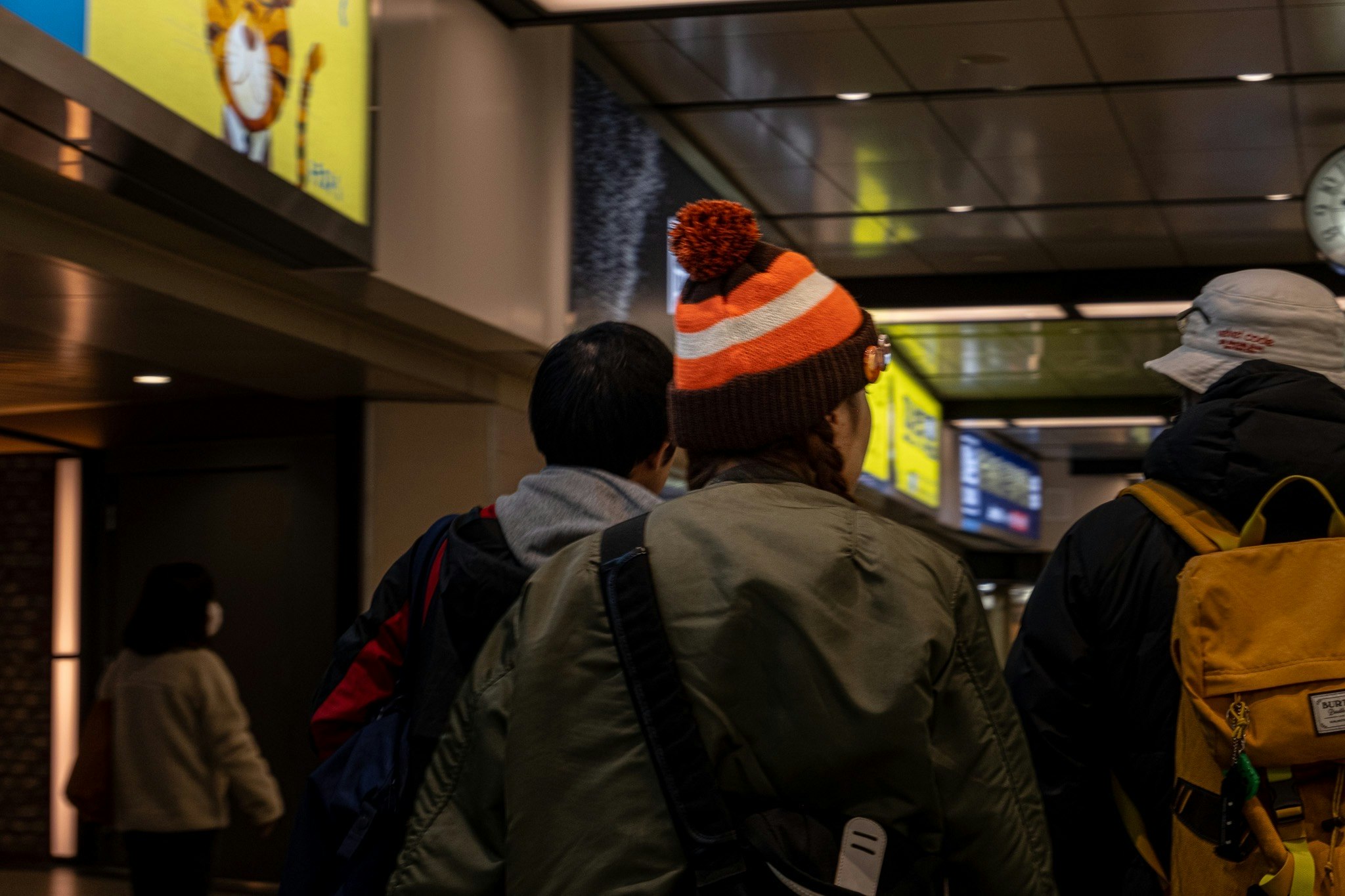 people in winter clothing moving through a station corridor