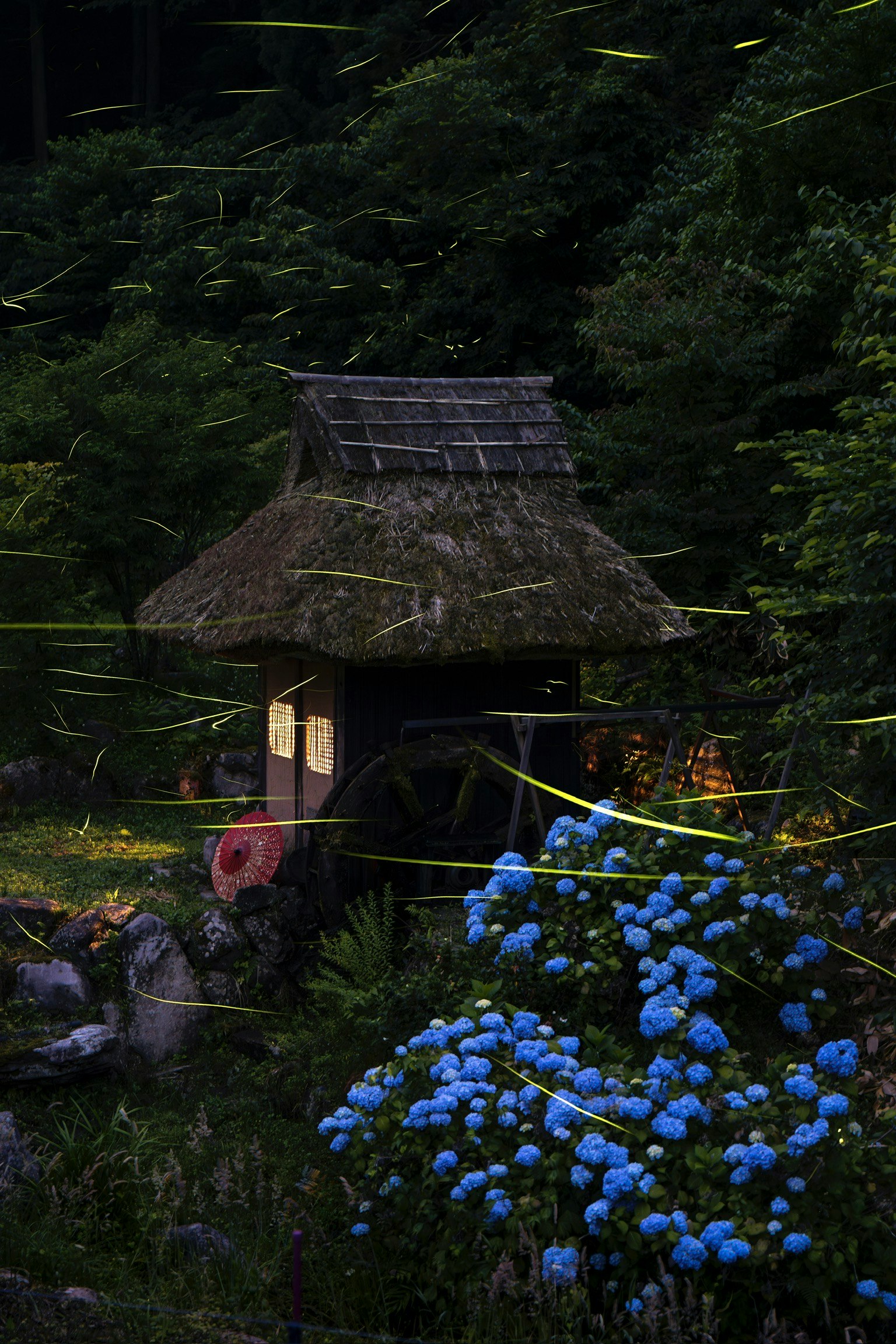 A thatched roof hut surrounded by glowing fireflies and blue flowers in a dark forest setting