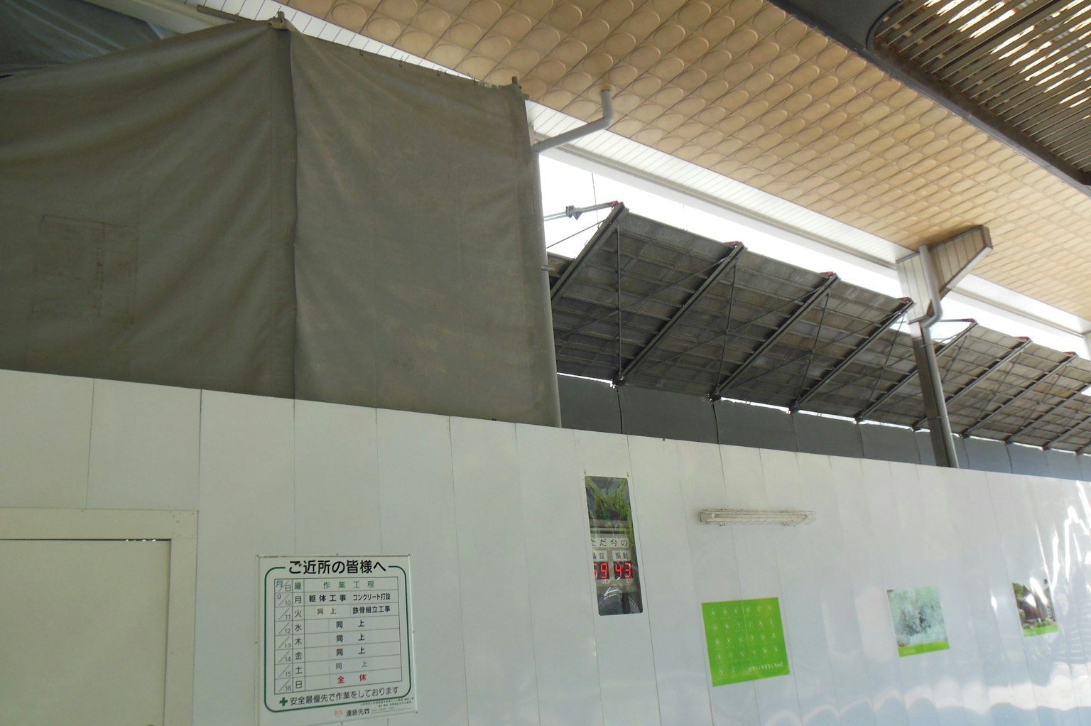 Spazio interno con una tenda grigia e vari poster sul muro