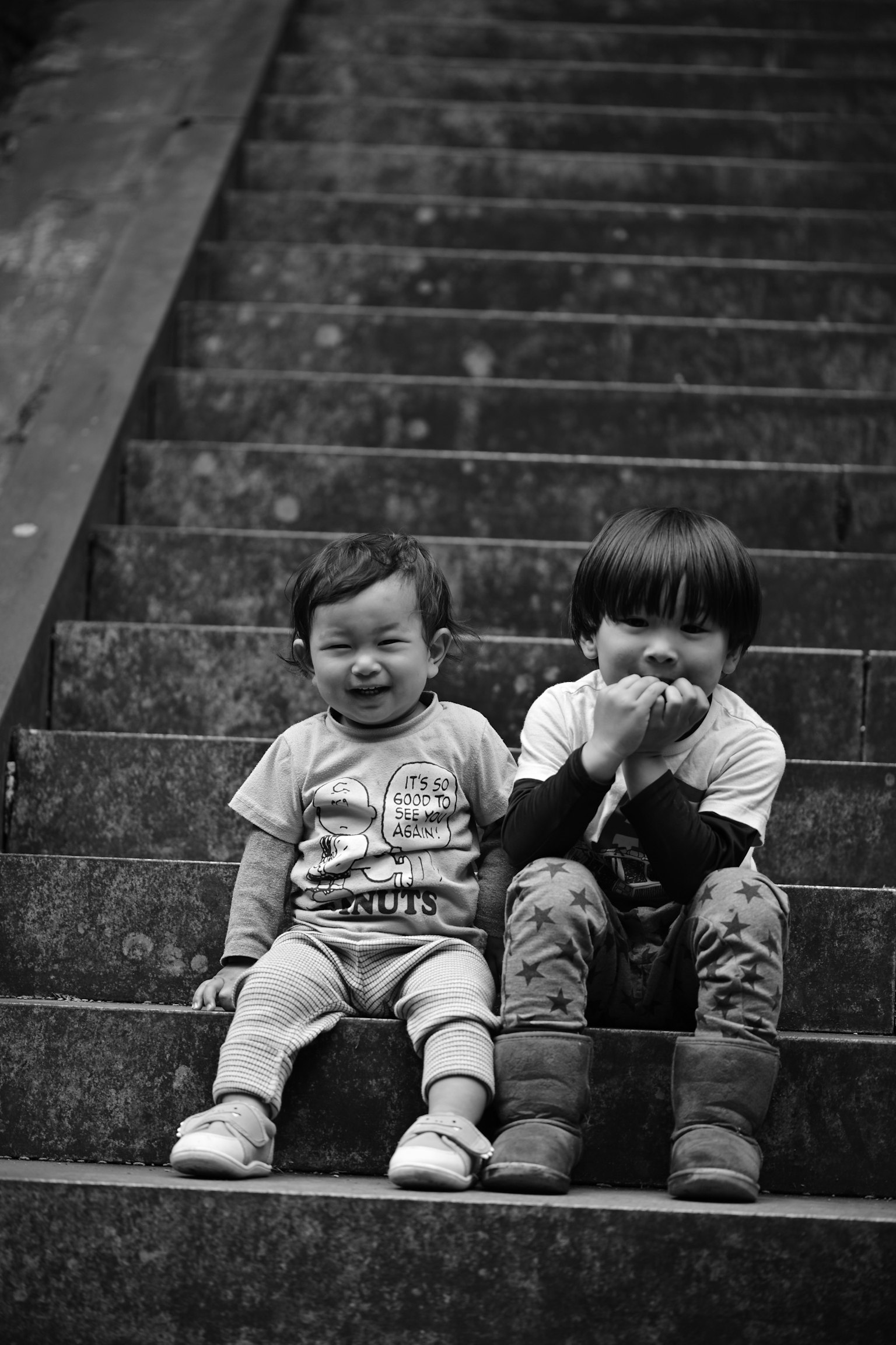 Due bambini seduti sulle scale uno piange e l'altro sorride