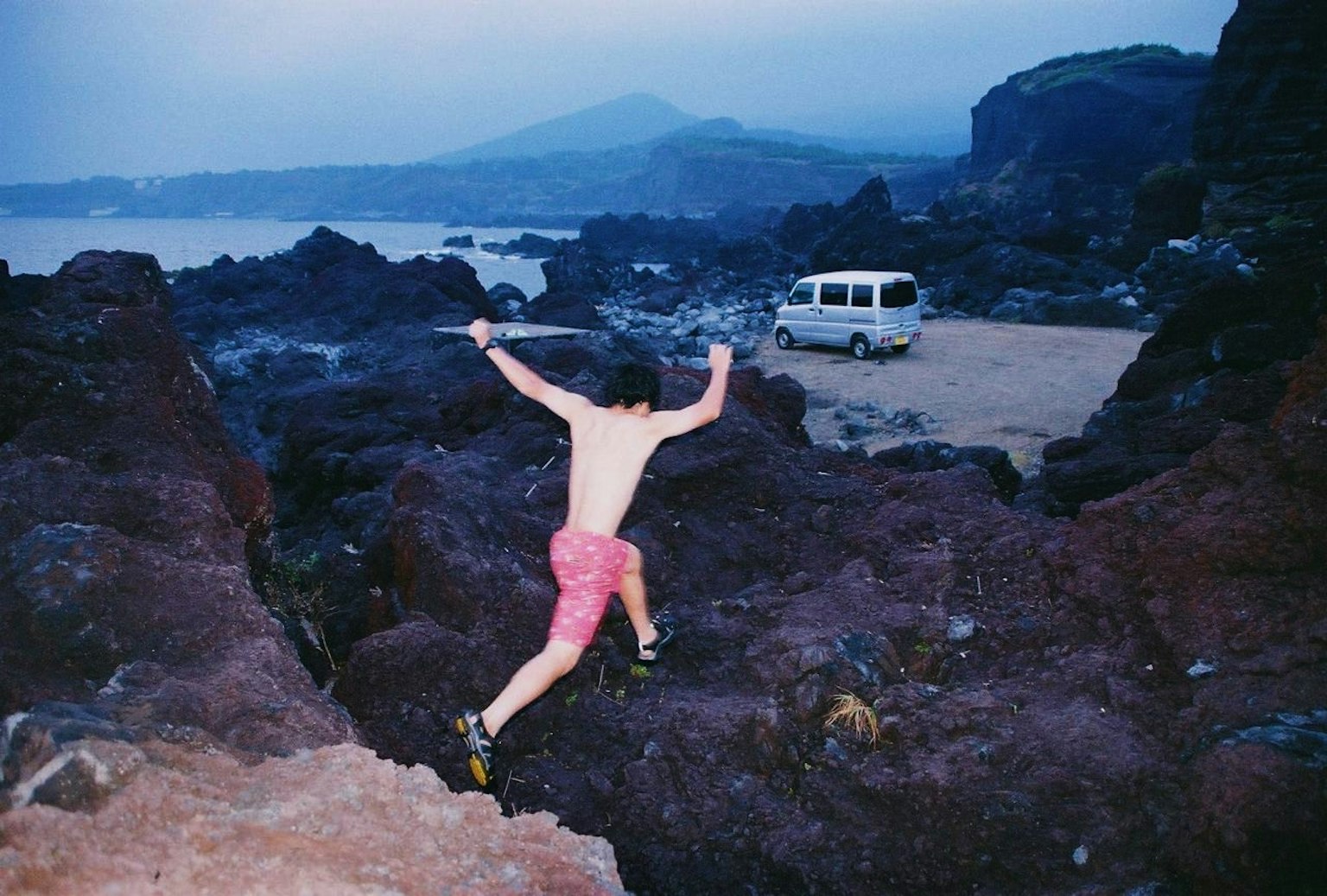 Uomo che salta su un terreno roccioso con una montagna sullo sfondo