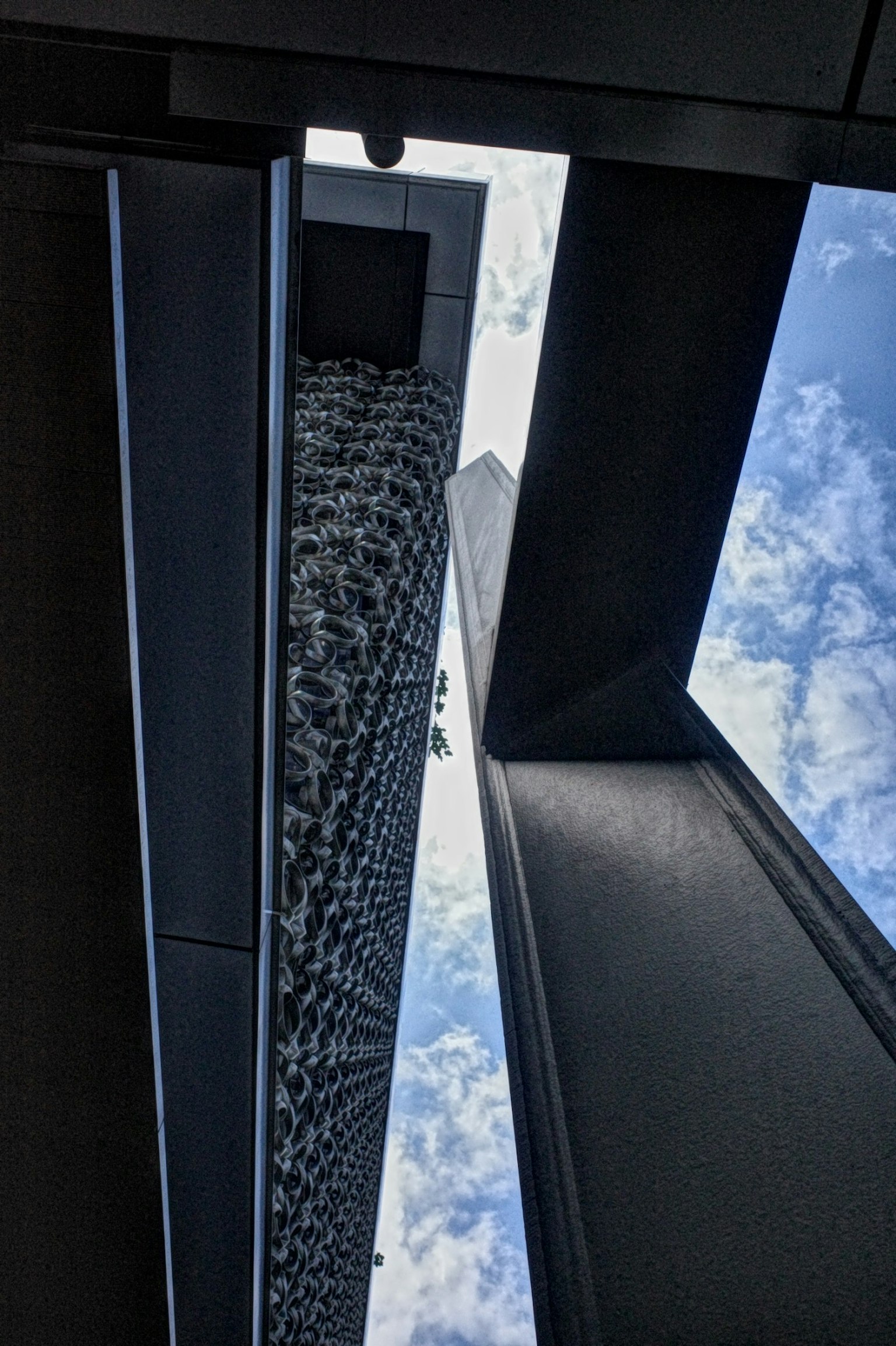 高層ビルの間から見上げた空の景色 建物の幾何学的なデザインと雲が特徴