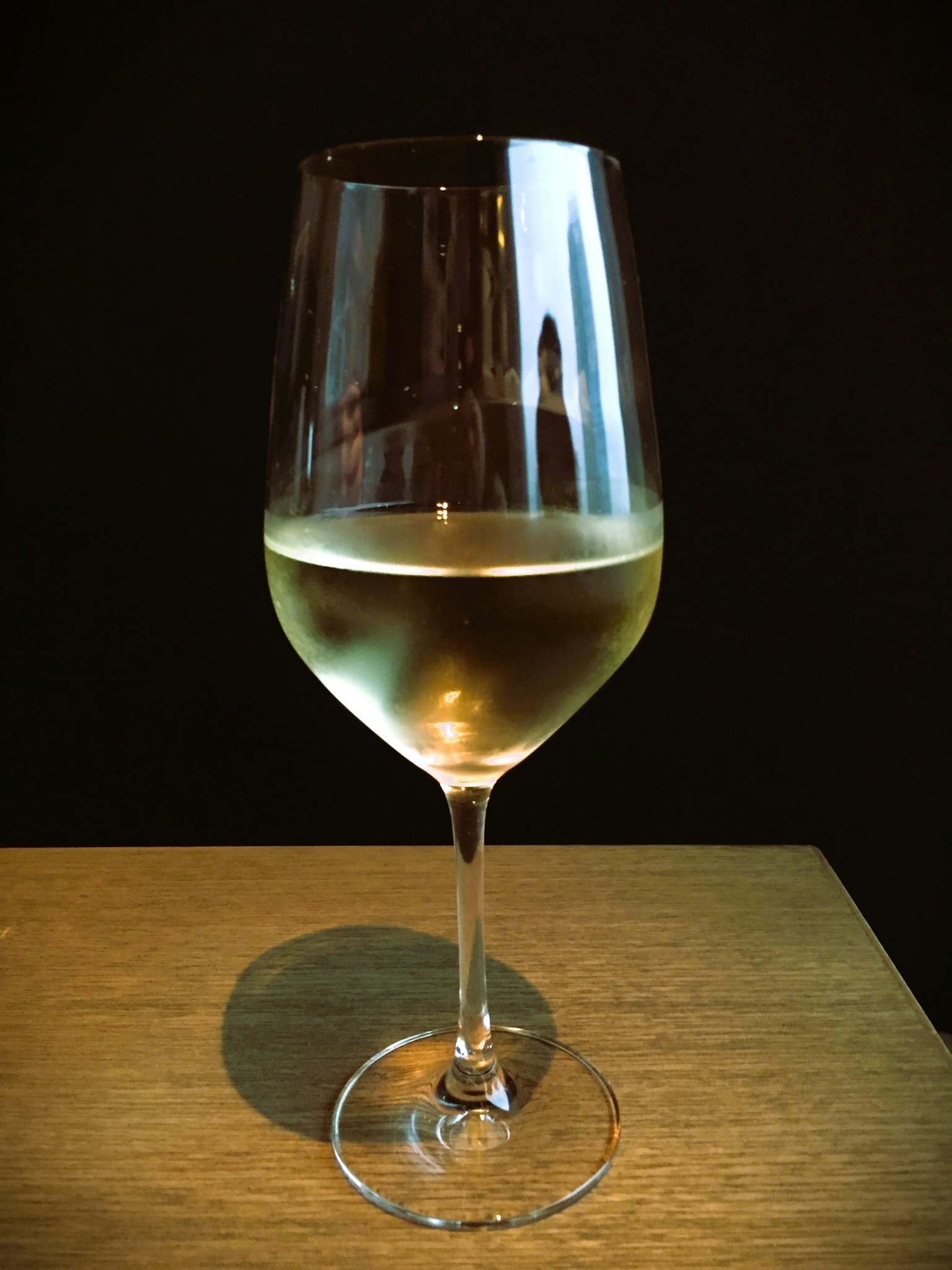 Una copa de vino blanco sobre una mesa de madera