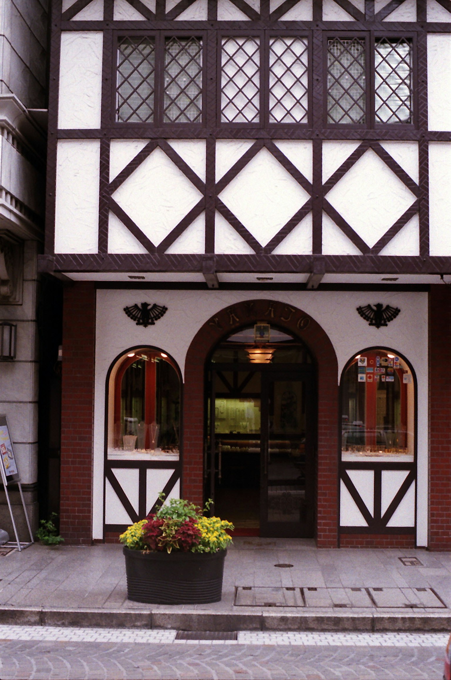 Entrance of a building with white and brown timber framing featuring a flower planter