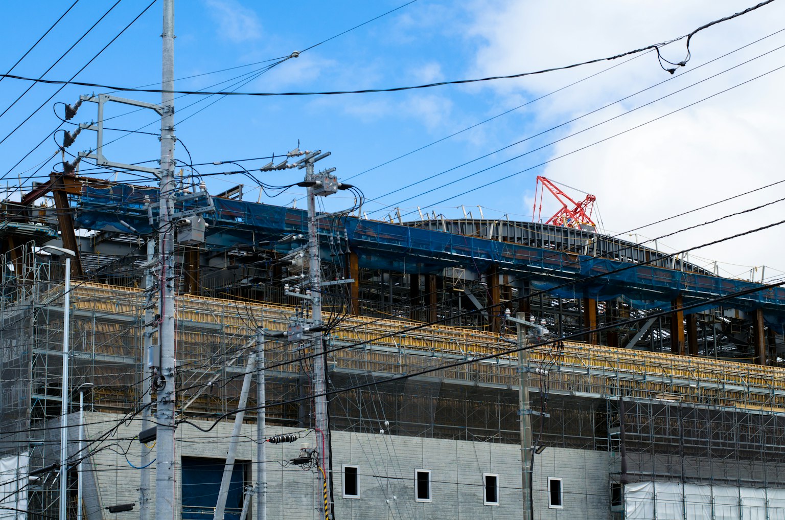 Cantiere di costruzione con edificio visibile e linee elettriche sotto un cielo blu