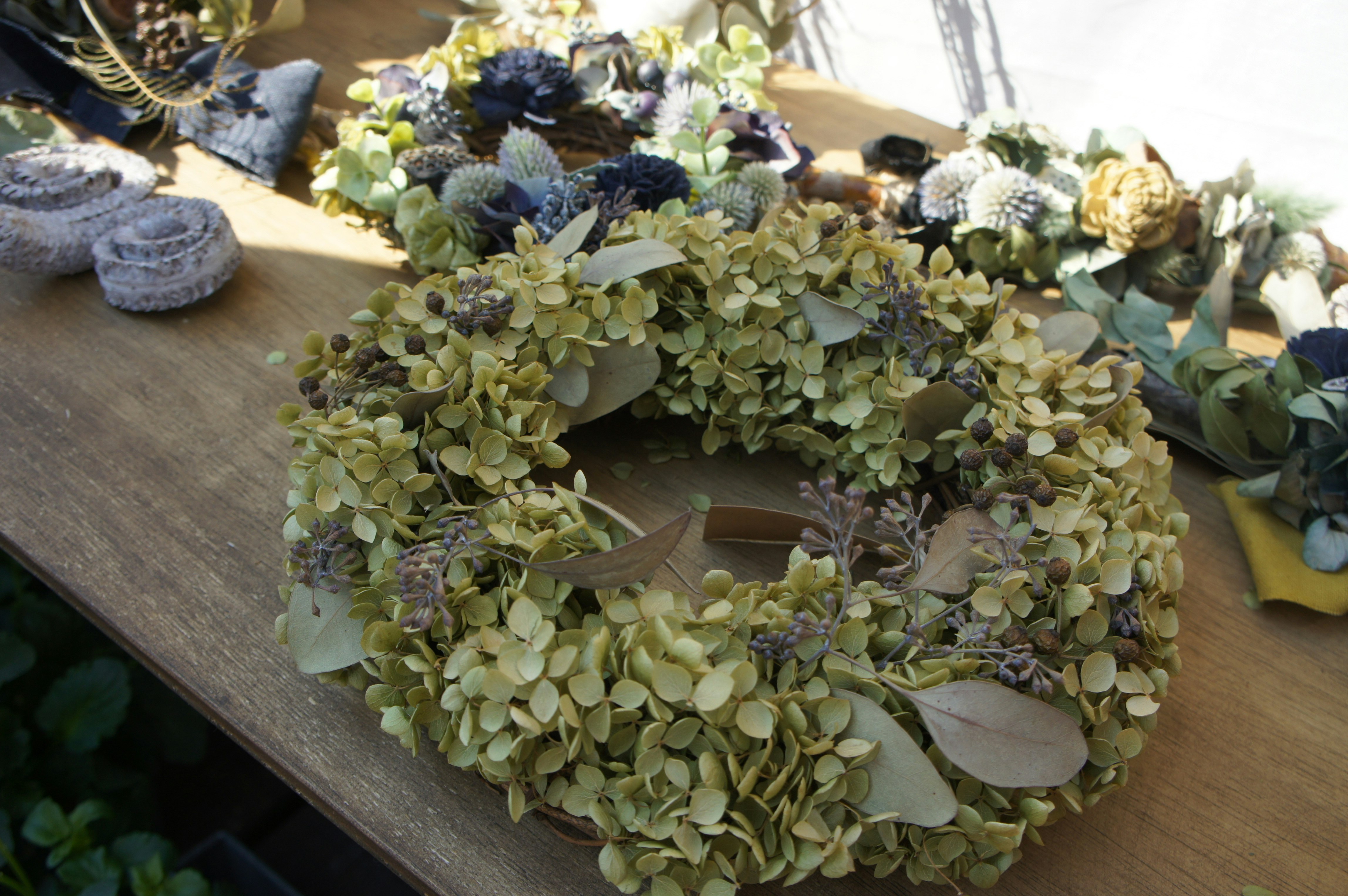 coronas florales verdes y ramos sobre una mesa de madera