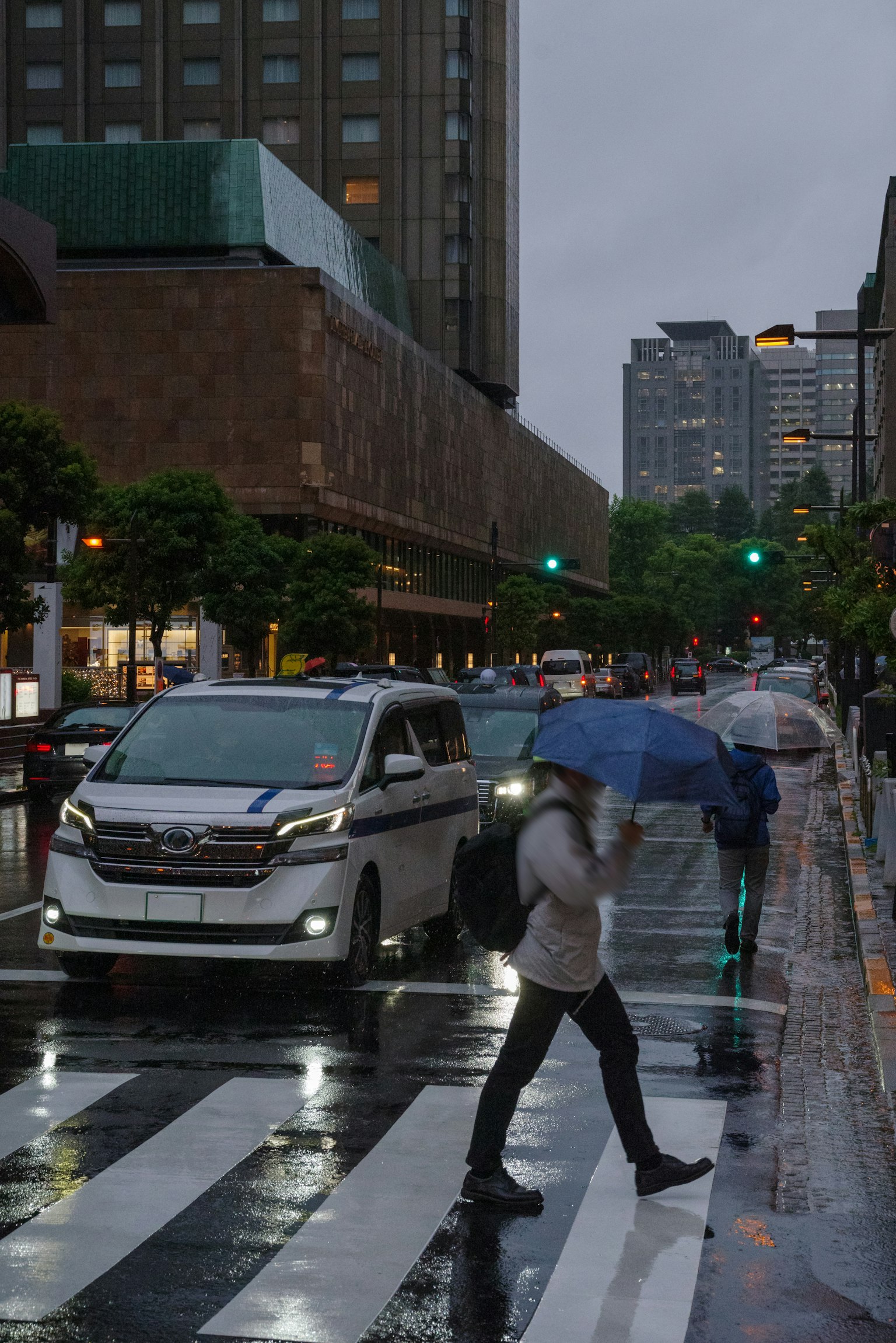 一个人撑着伞在雨中的城市环境里过马路