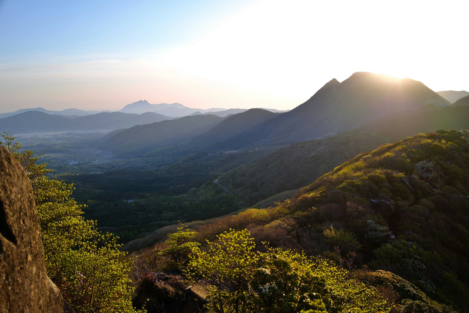 Panoramablick auf Berge mit leuchtendem Sonnenuntergang und üppigem Grün