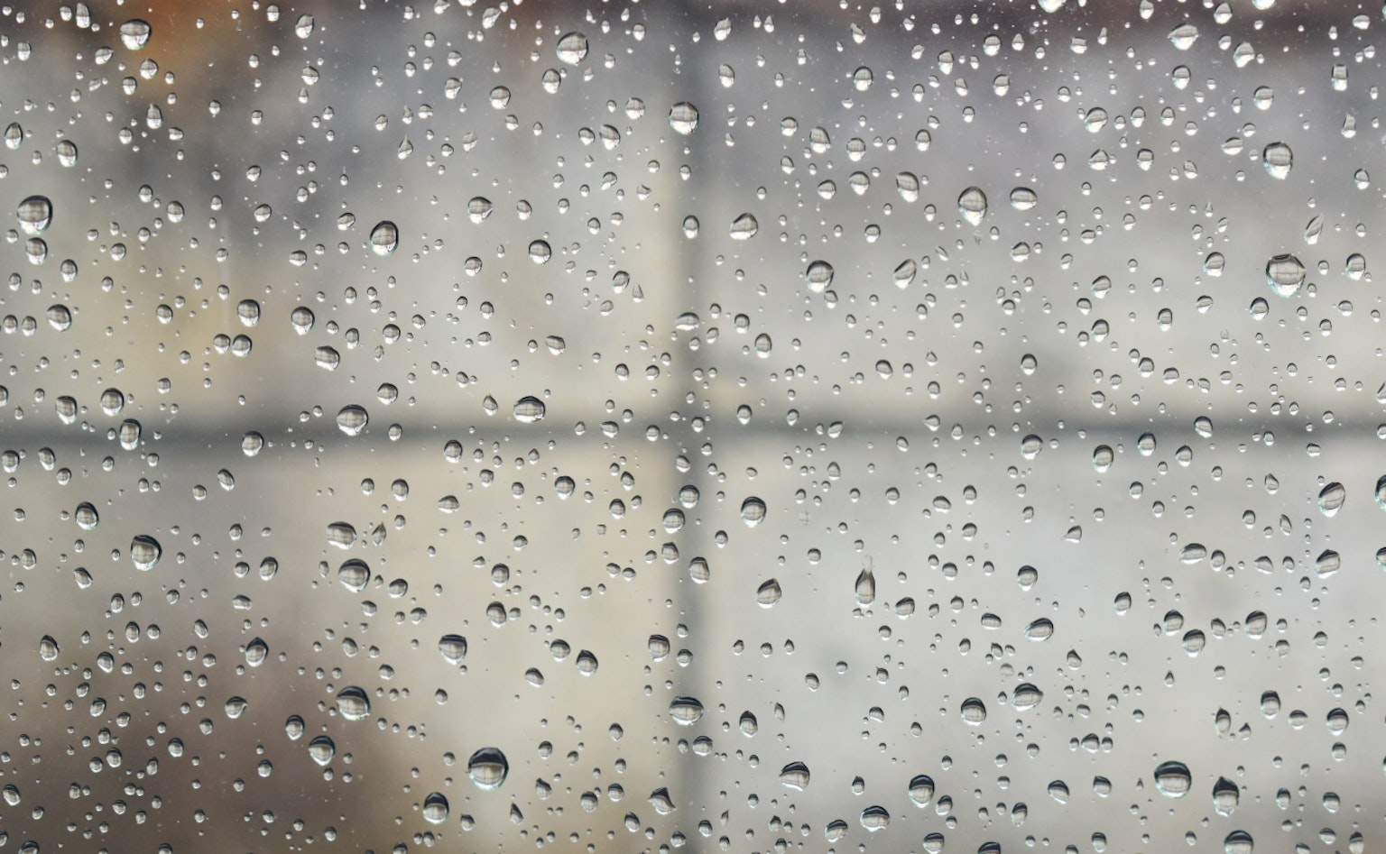 Primer plano de gotas de lluvia en una ventana con fondo borroso