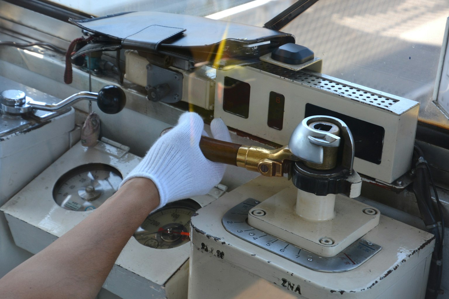 A gloved hand operating a boat control device