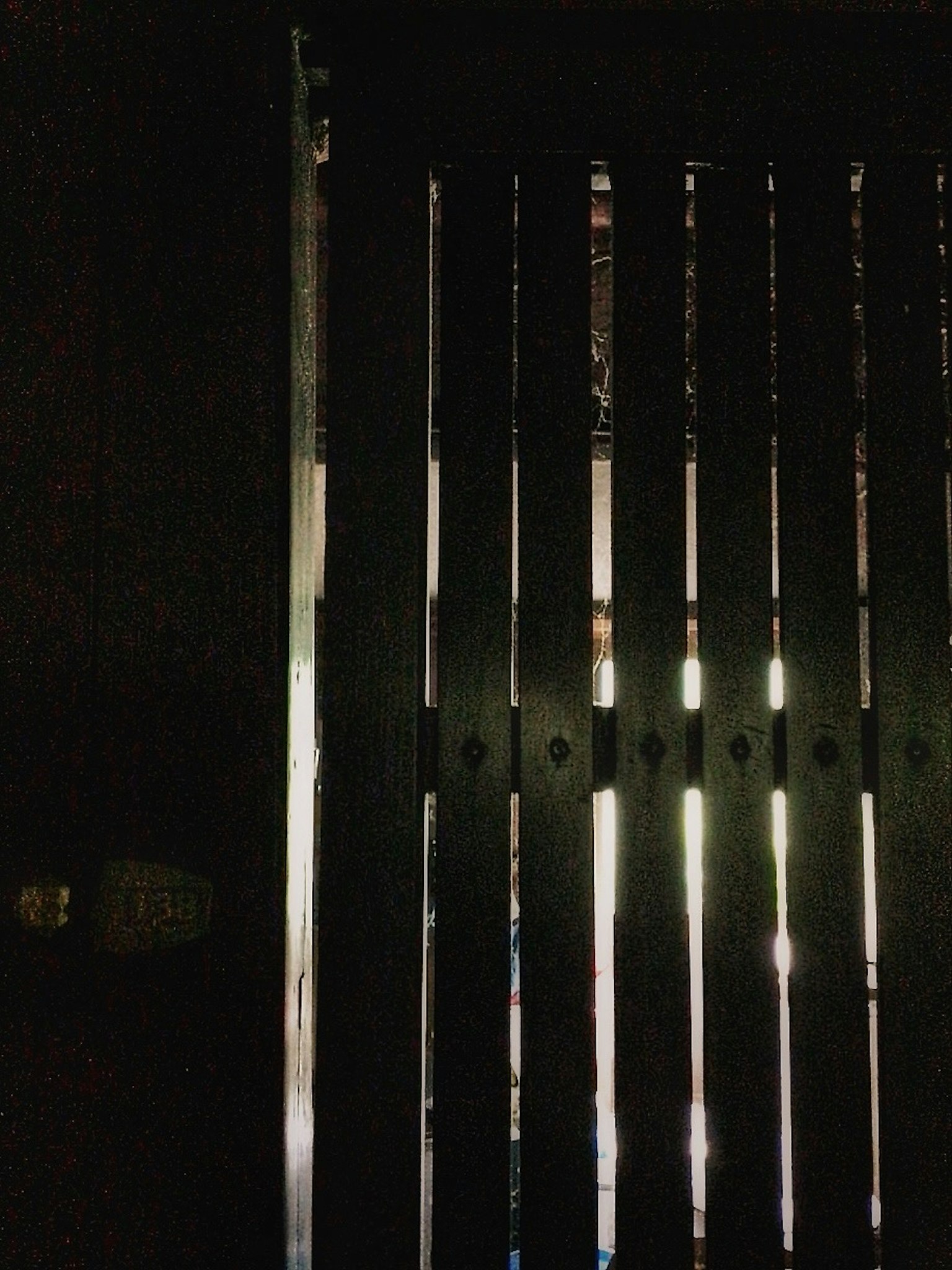 一扇木製百葉門的圖片背景為黑暗光線透過縫隙