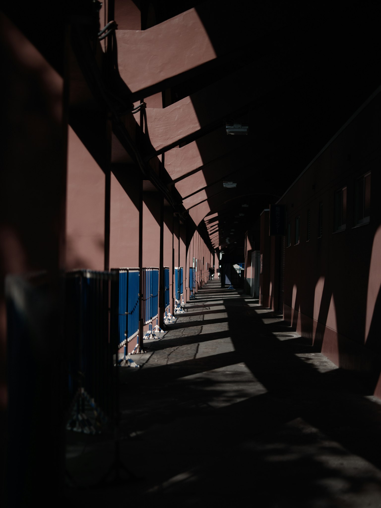 Un lungo corridoio con pareti rosse e pannelli blu che proiettano ombre