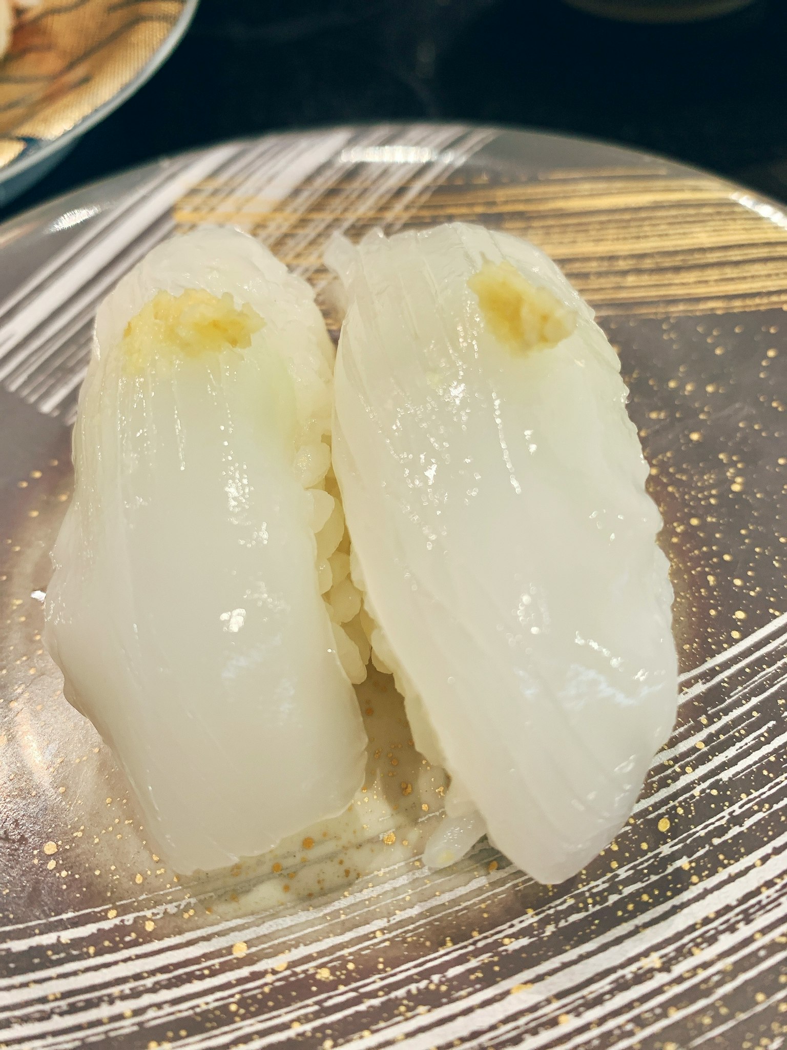 장식적인 접시에 놓인 두 개의 흰색 초밥